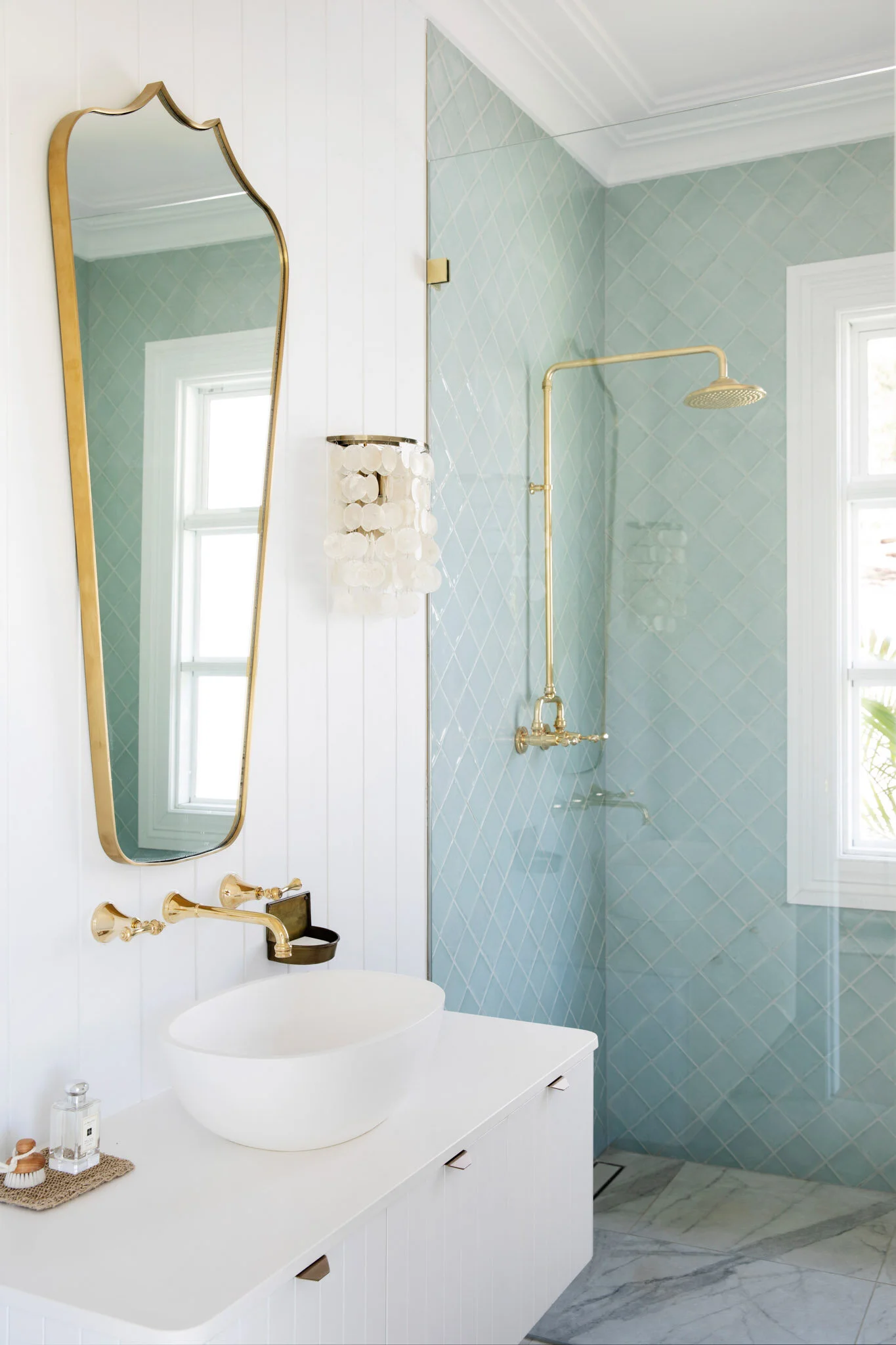Three Birds Renovations House 13 Pool House bathroom with pale blue tiled shower, brass fixtures, a vessel basin and sculptural framed mirror.