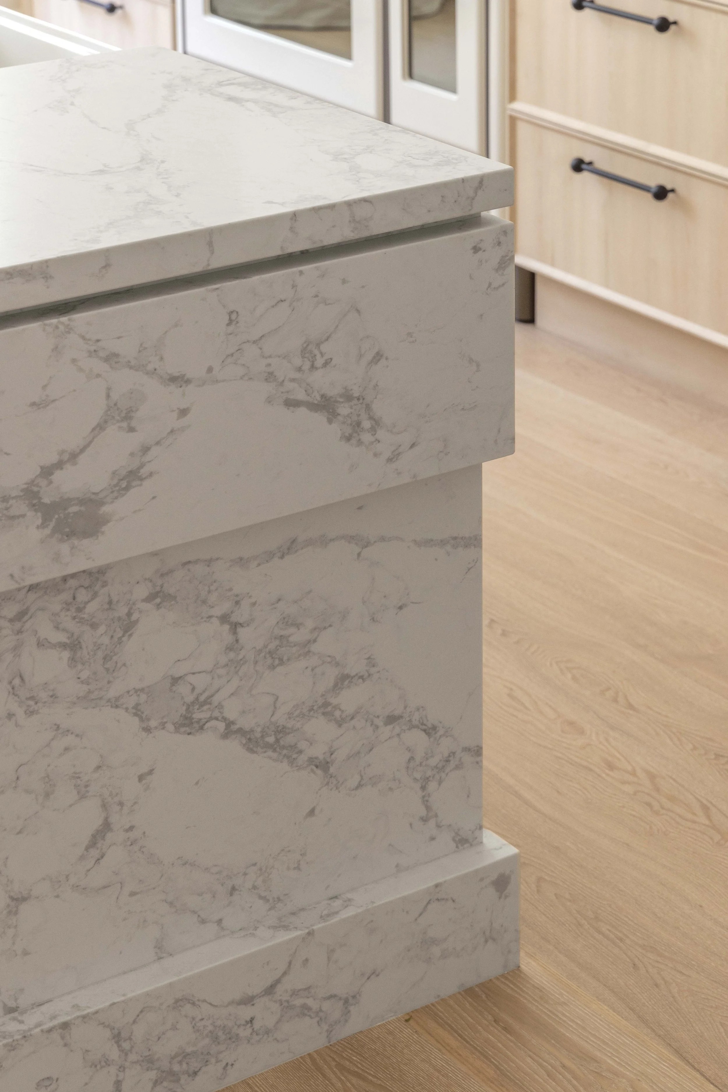 Three Birds Renovations House 16 kitchen island detail with marble stone waterfall edge and warm timber flooring.