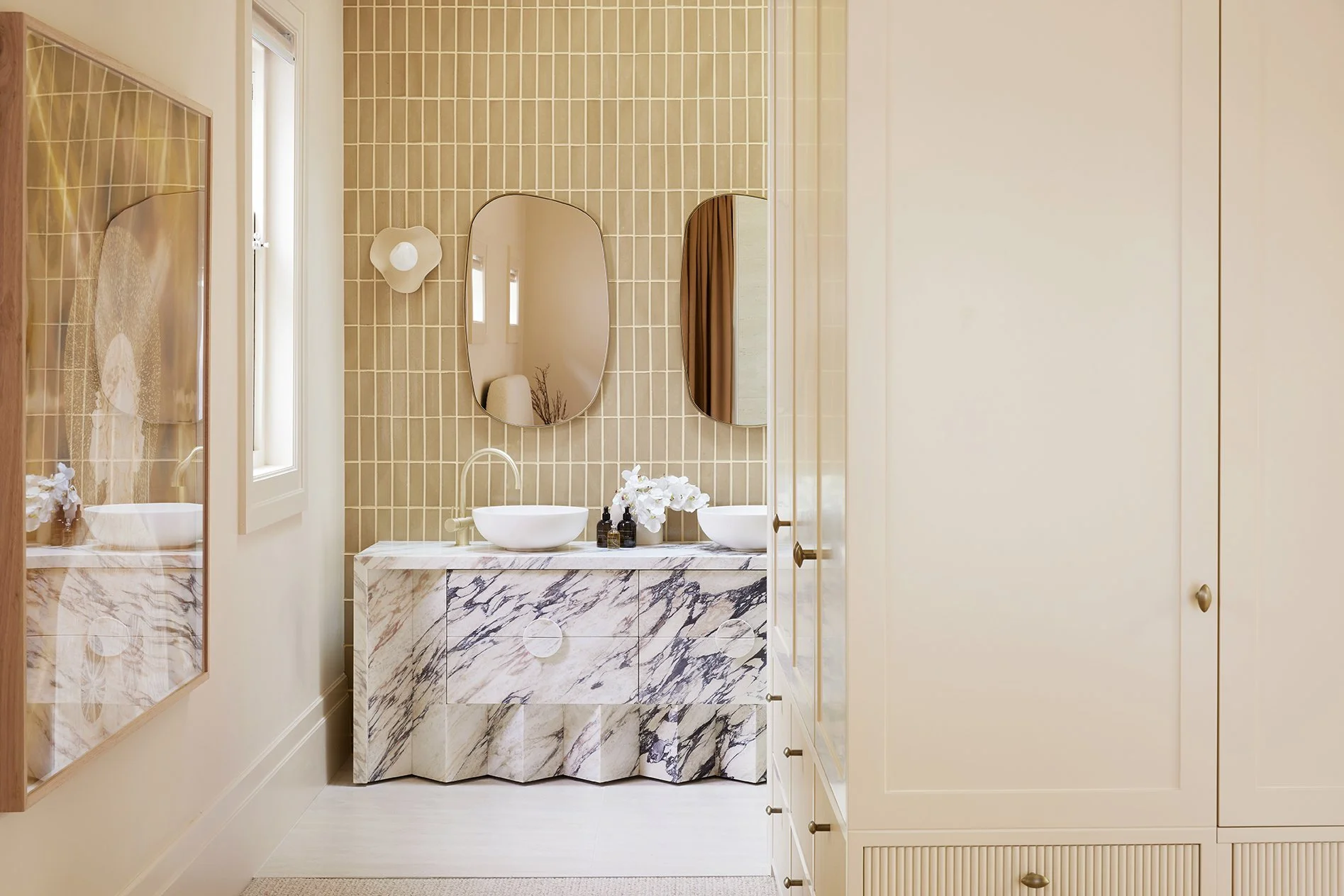 Three Birds Renovations House 17 bathroom with marble vanity, curved mirrors, textured tiles and refined contemporary styling.