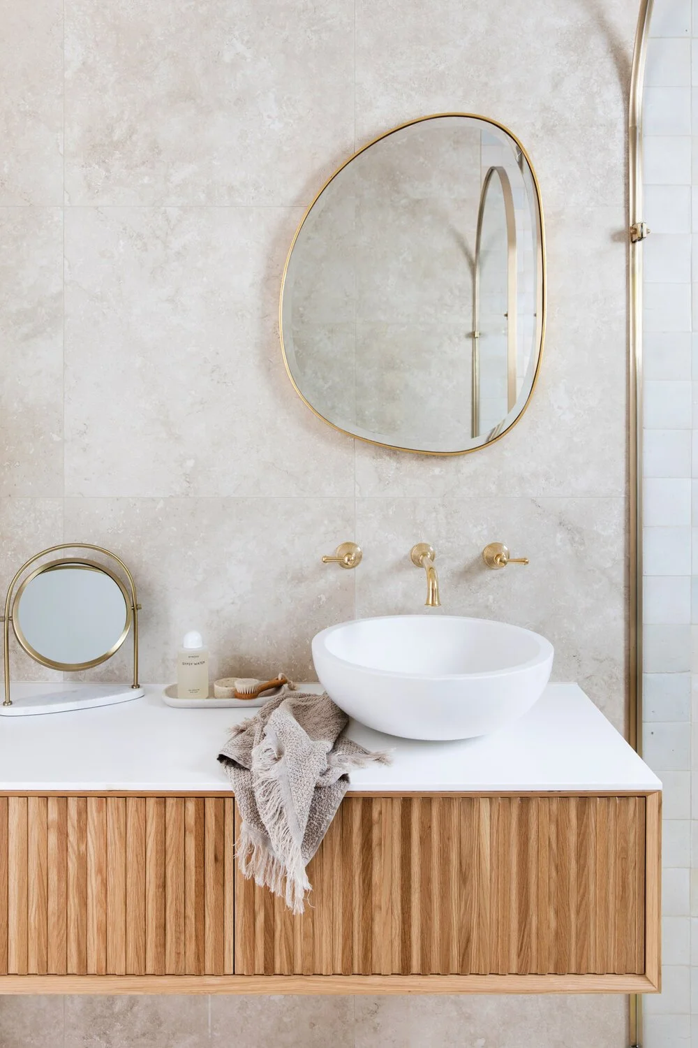 Three Birds Renovations House 13, modern bathroom with fluted timber vanity, round brass mirror, white vessel basin, and brushed gold tapware showcasing elegant contemporary Australian design.