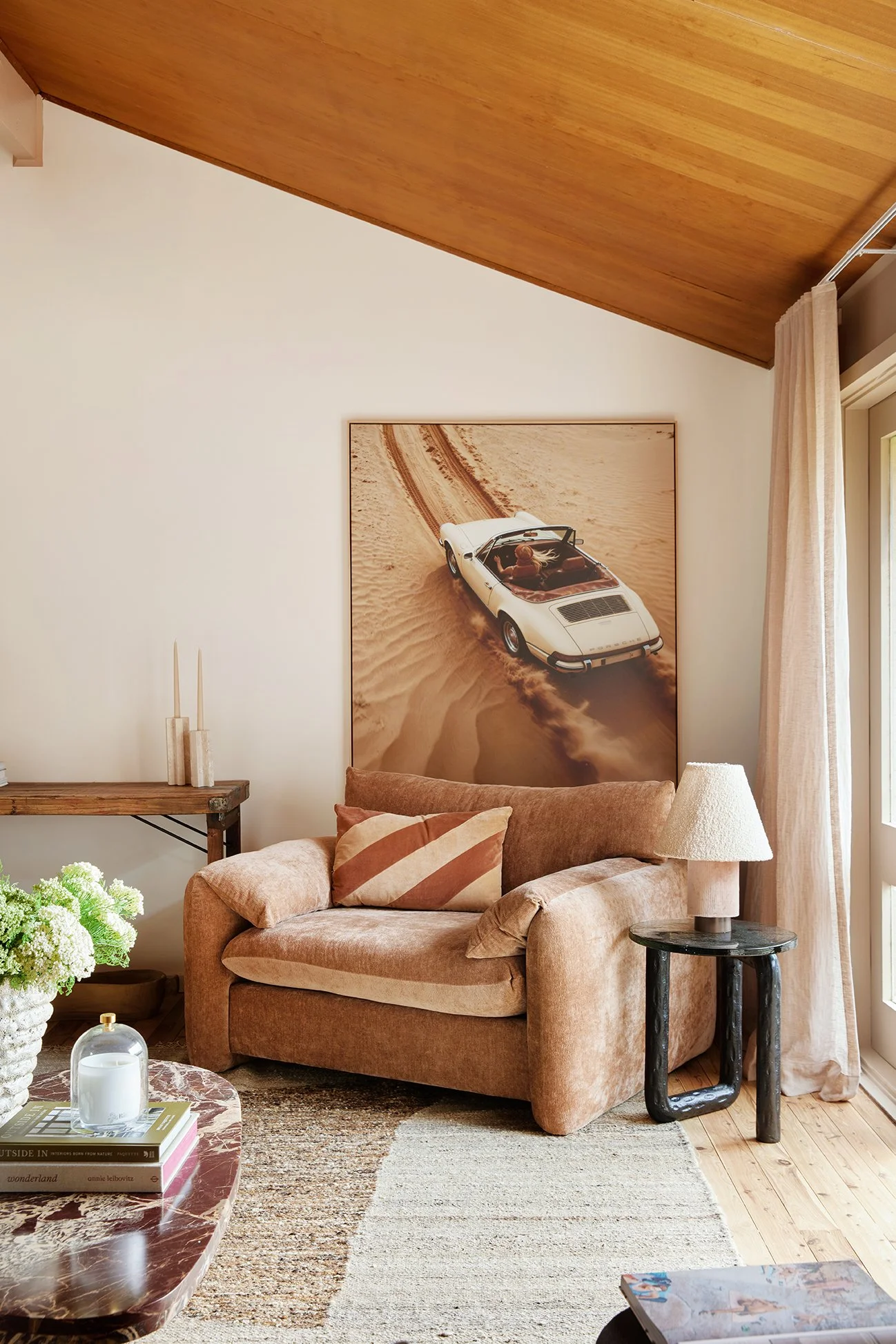 Three Birds Renovations Living Room Transformation with cosy armchair, vintage car artwork, marble coffee table and warm neutral styling.