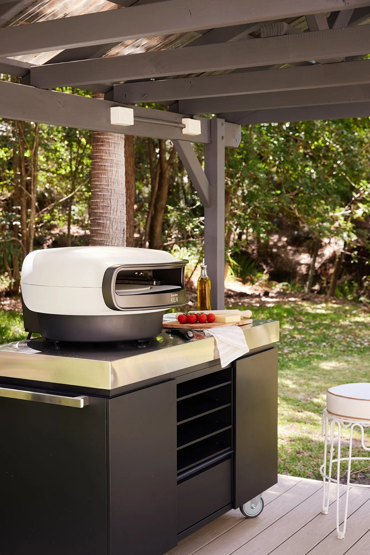 Three Birds Renovations Eclectic Escape outdoor entertaining area with covered pergola, portable pizza oven, stainless steel benchtop and tropical garden surrounds.