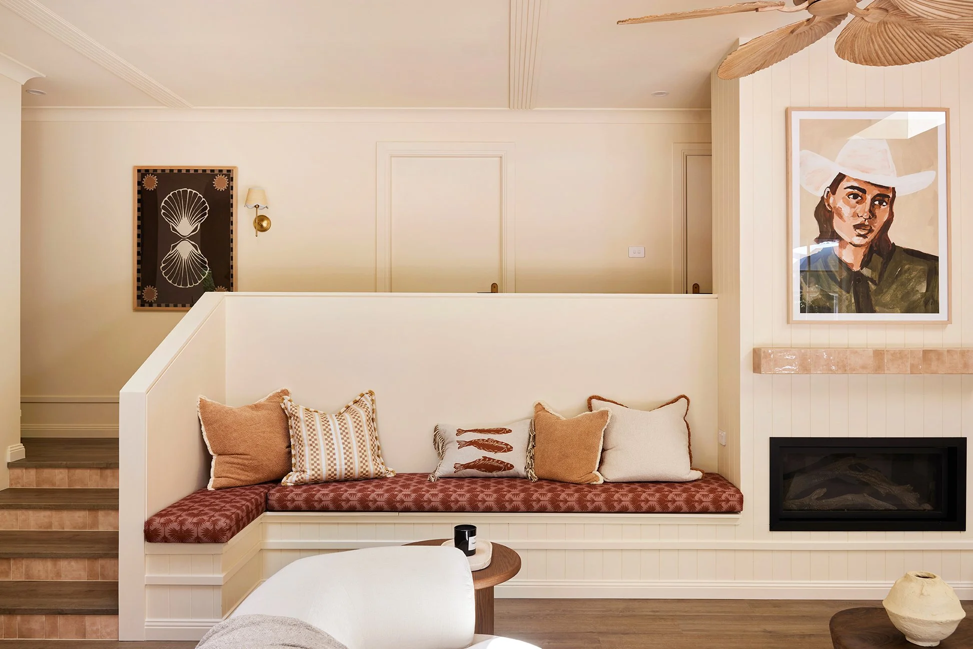 Three Birds Renovations Eclectic Escape living room after renovation featuring custom bench seating with patterned cushions, timber flooring and a modern built-in fireplace.