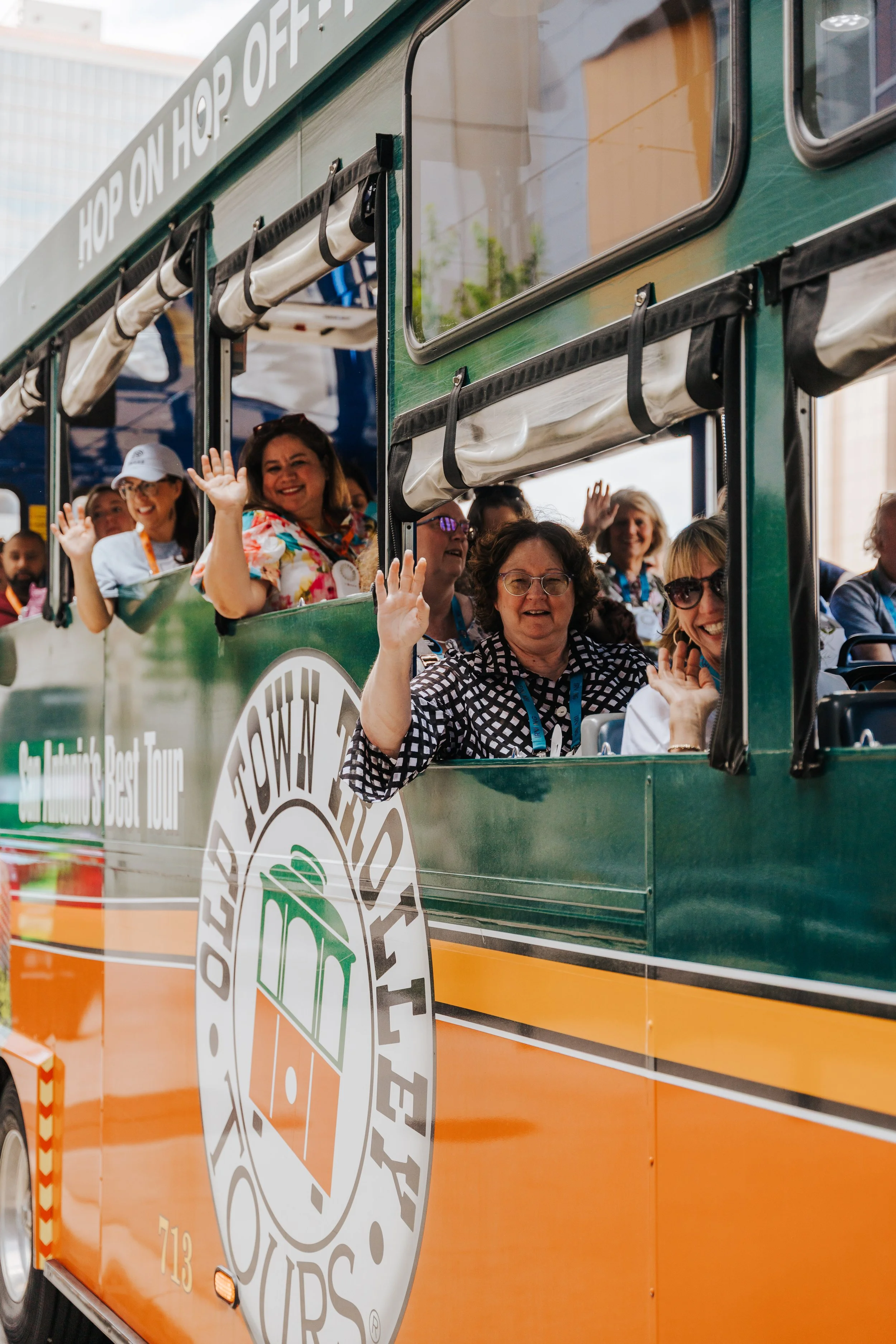 Excited group waving from an Old Town Trolley hop on hop off tour bus in downtown San Antonio.