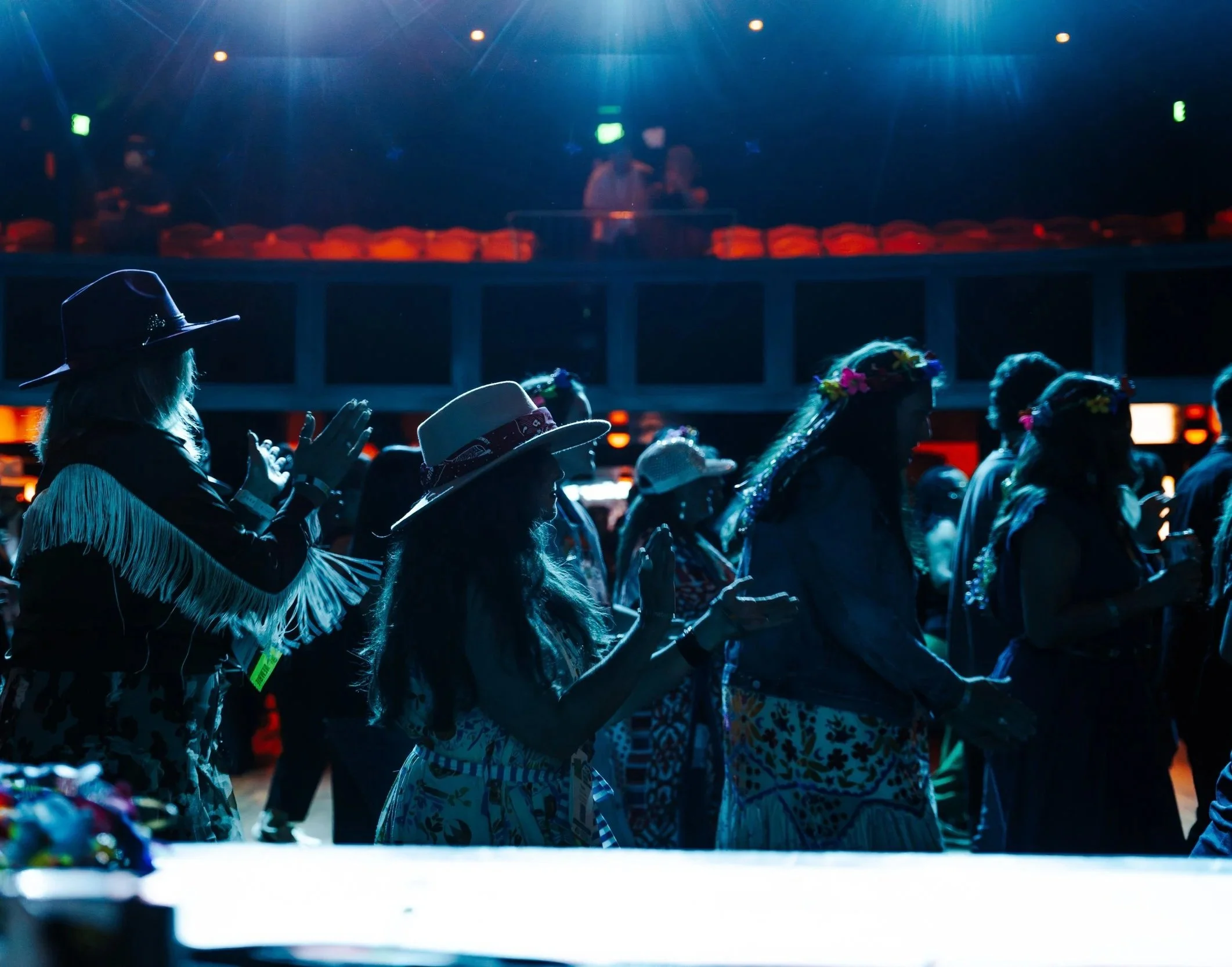 Silhouetted crowd dancing under stage lights at a live indoor corporate entertainment event.