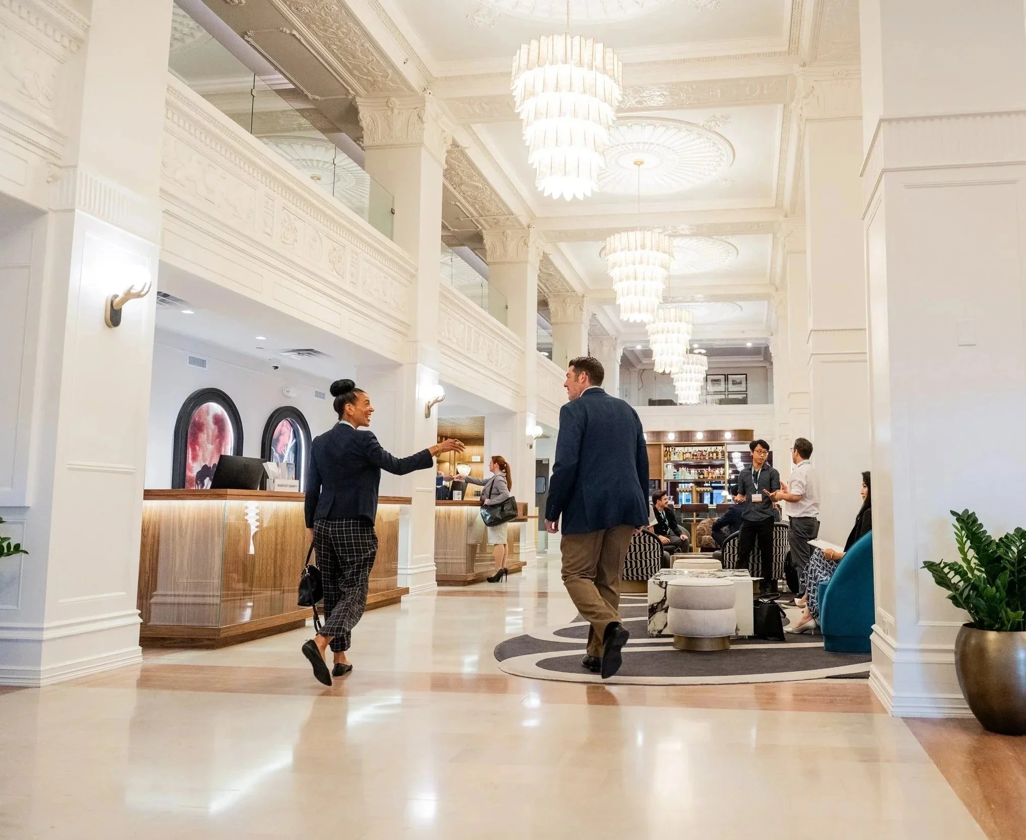 A guest being greeted by a professional concierge host in a grand hotel lobby with crystal chandeliers for hospitality content creation.