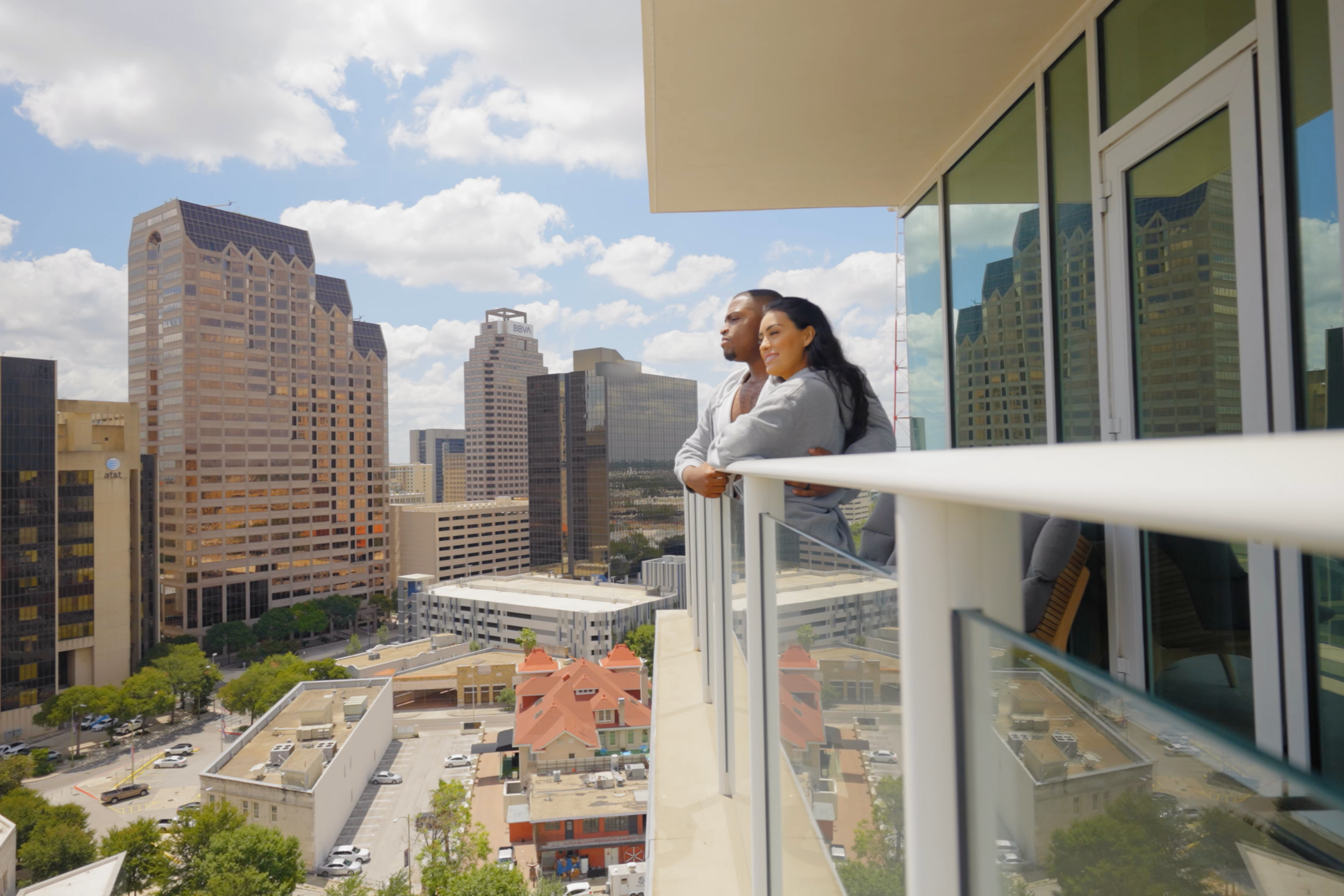 Couple overlooking the downtown San Antonio skyline from a hotel balcony for travel and hospitality photography.
