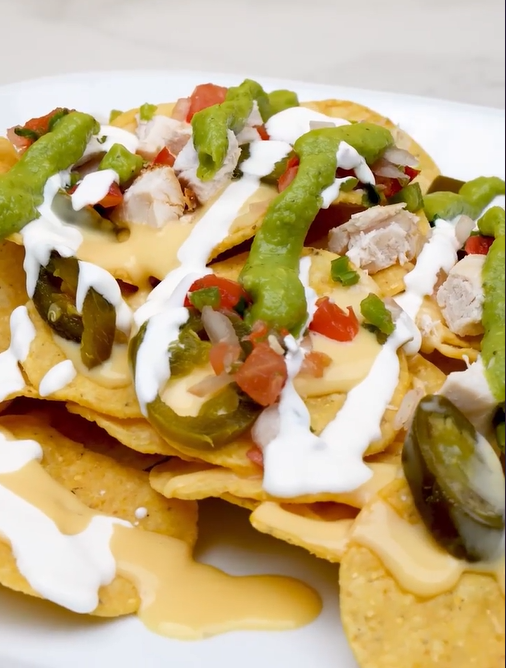 Loaded nachos topped with queso, guacamole, jalapeños and pico de gallo for restaurant content creation.
