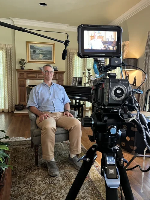 Man sitting in a well-decorated room in-front of a camera for an interview.