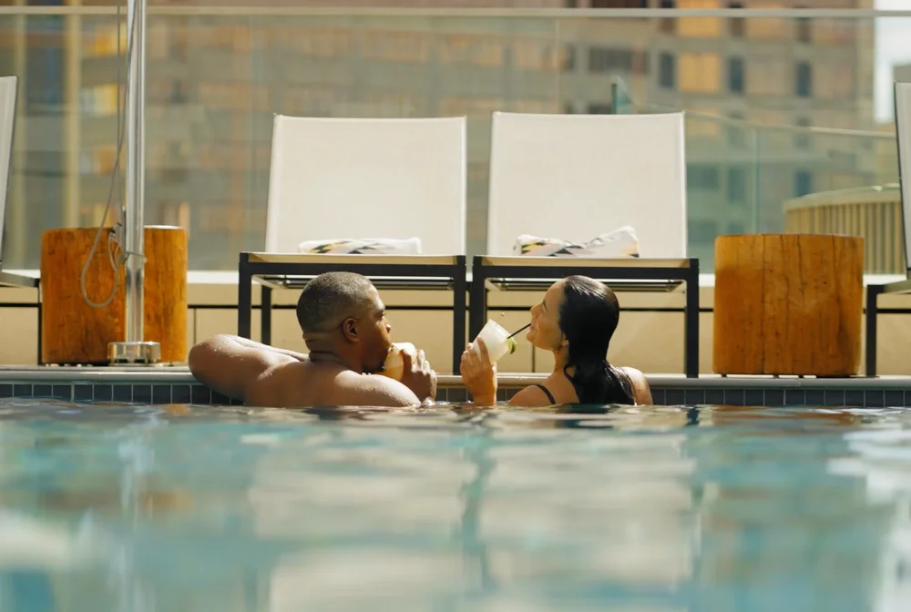 Couple enjoying drinks in a rooftop hotel pool overlooking the downtown San Antonio skyline.