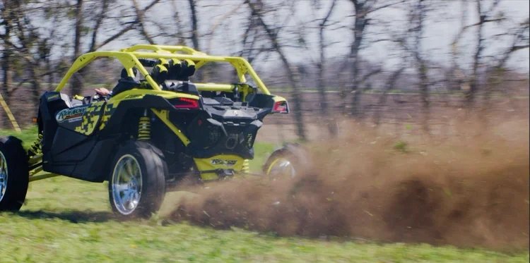 Action shot of a yellow off-road vehicle kicking up dirt in a field for the Granger Smith Holler video.