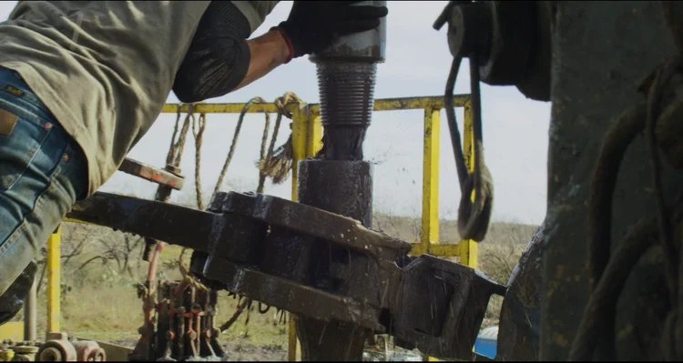 Worker operating machinery on an oil rig, capturing the grit of the country music video.