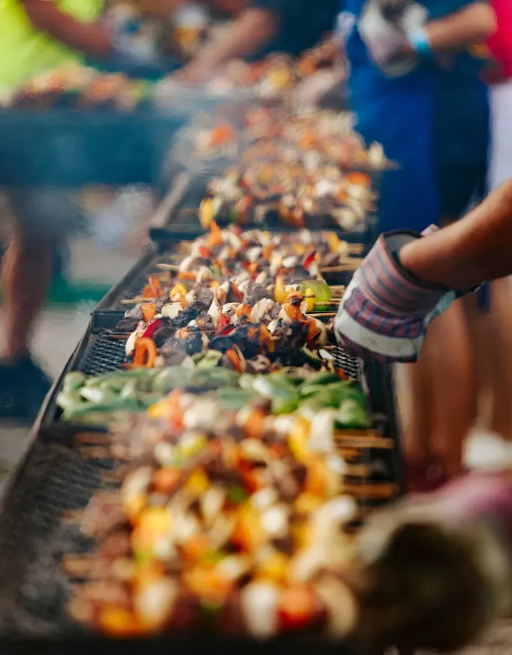 
Colorful meat and vegetable kabobs smoking on an outdoor grill at a San Antonio food festival.