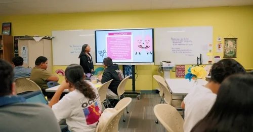 Student presents educational content on a monitor to classmates in a modern classroom.