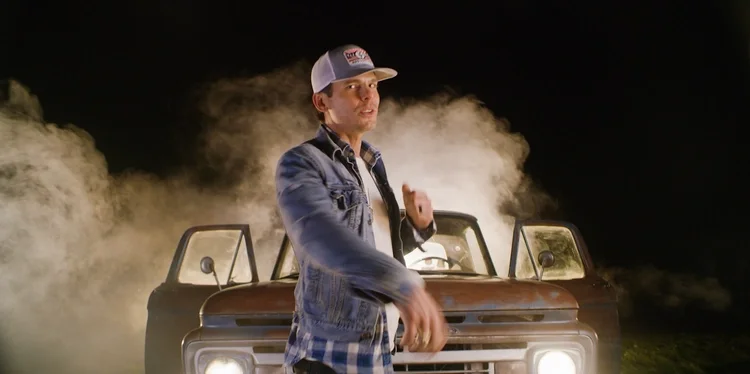 Granger Smith performing in front of a vintage truck with smoke and lights for the Holler music video.