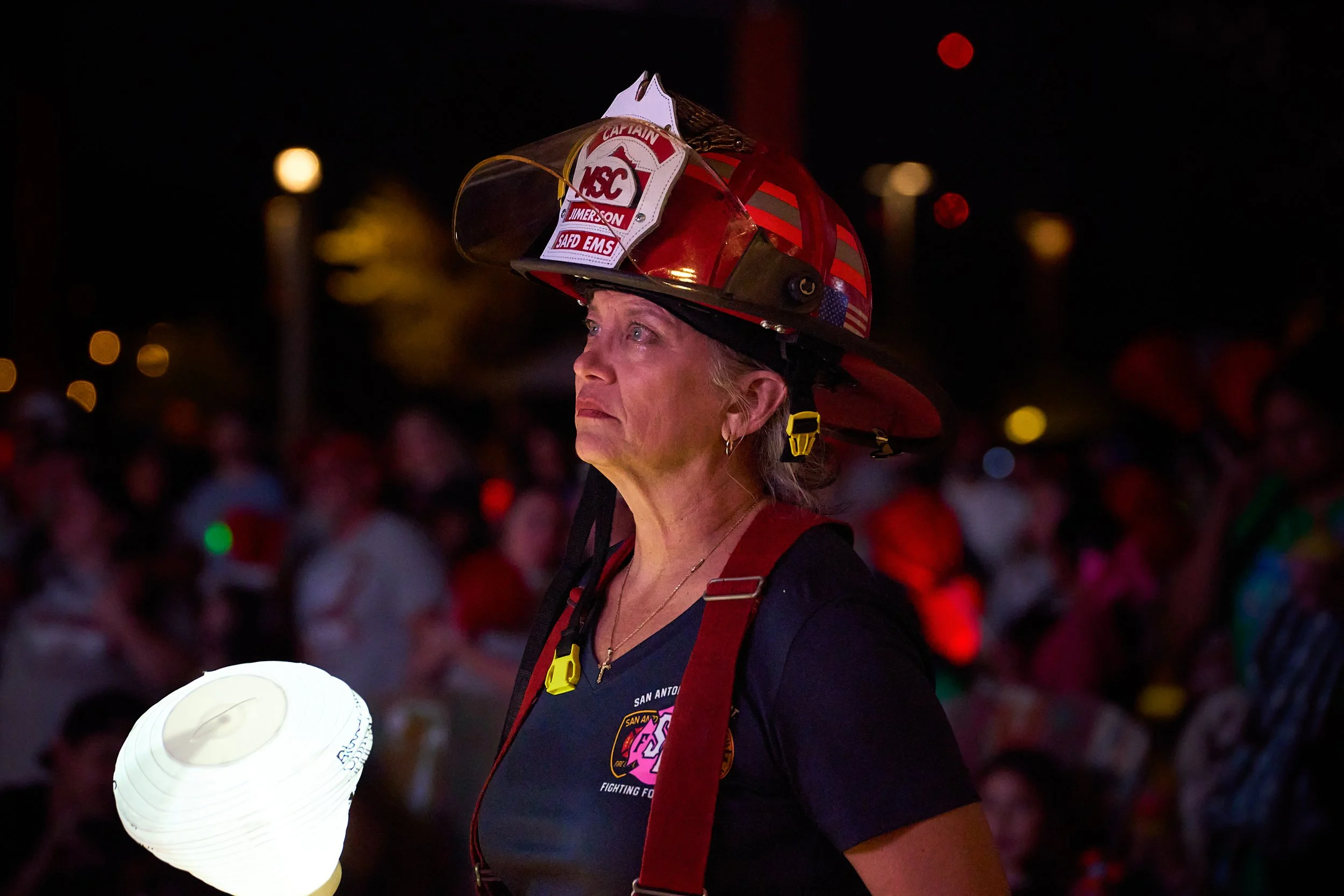 San Antonio female firefighter holding a glowing lantern at a nighttime charity awareness event.