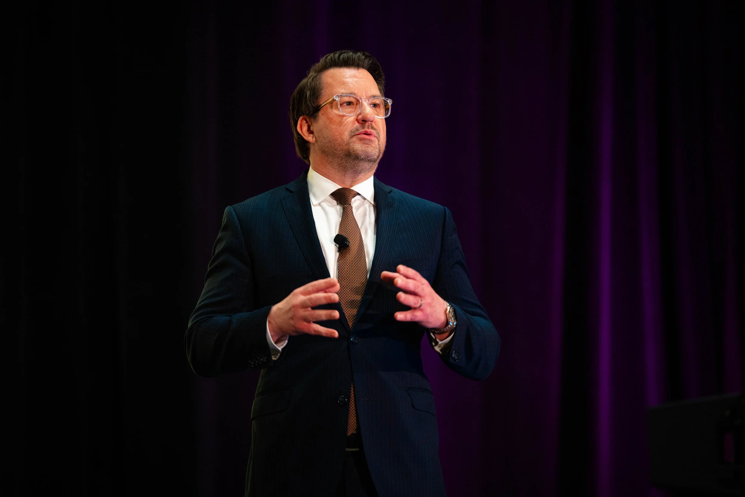 Corporate keynote speaker presenting on stage at a professional conference event in San Antonio.