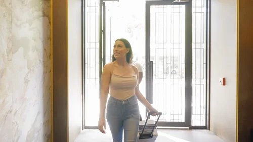 Woman with luggage entering Thompson Hotels.