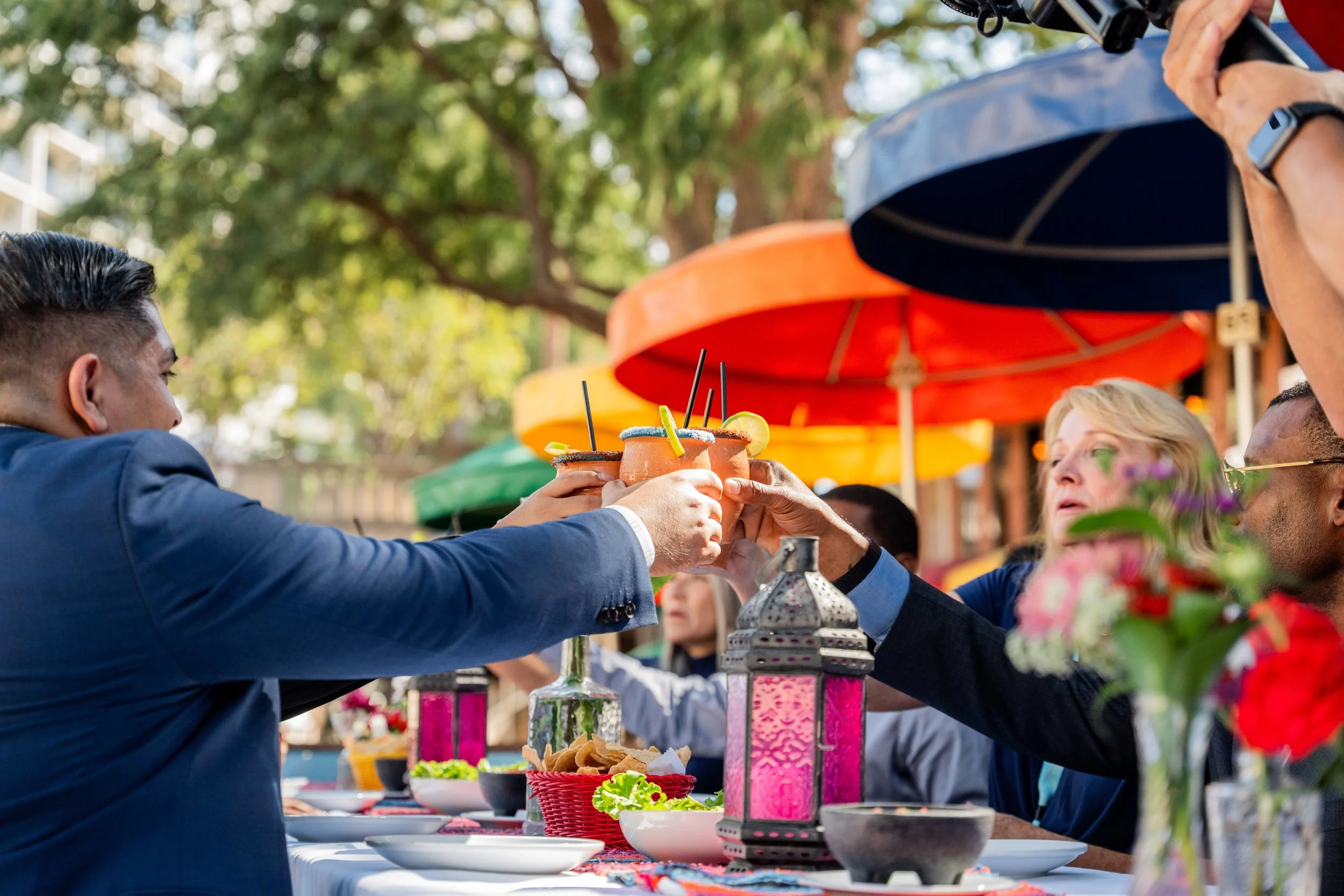 Group toasting with margaritas at a colorful outdoor dining event on the San Antonio River Walk.