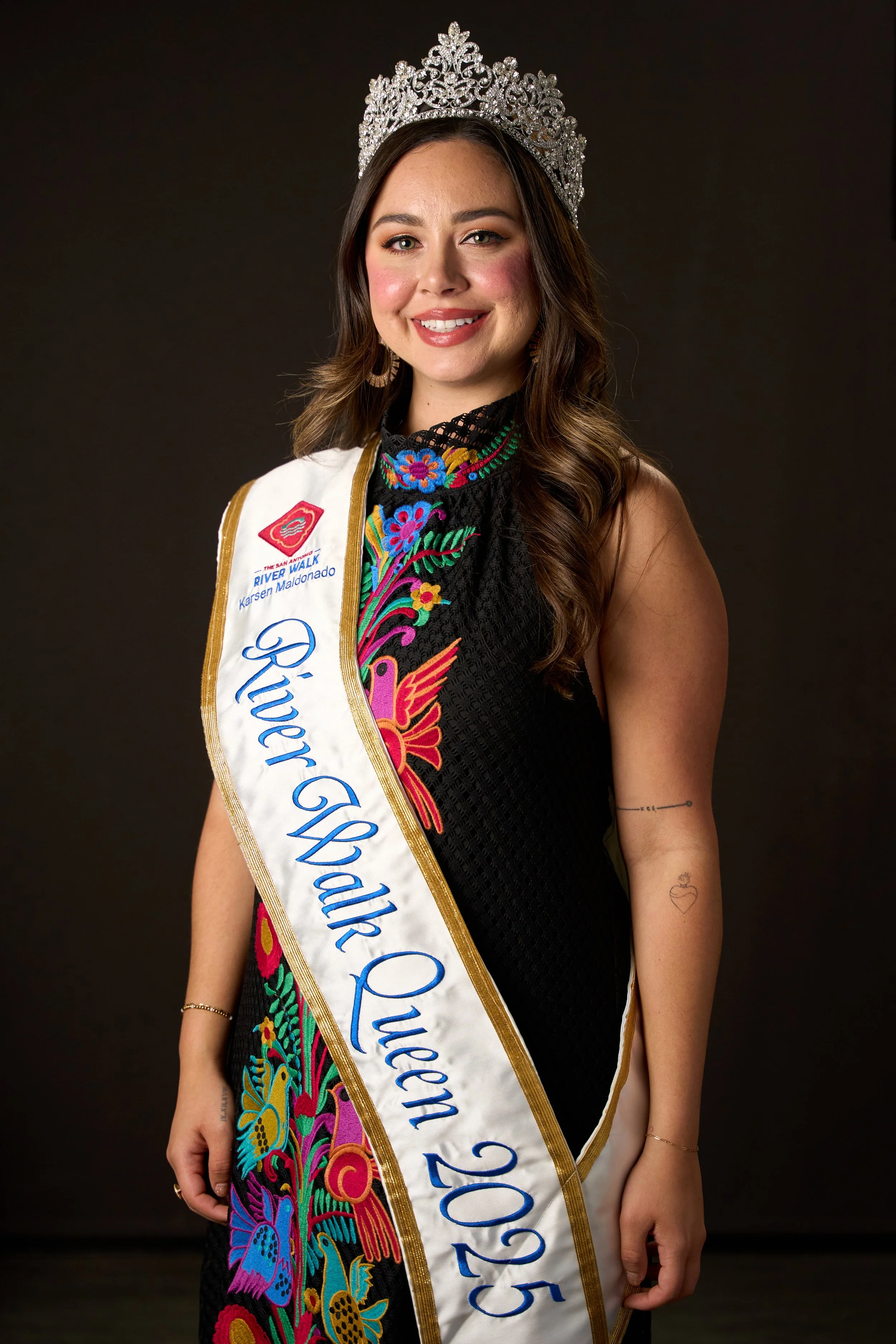 Formal studio portrait of San Antonio River Walk Queen 2025 wearing crown and embroidered gown.
