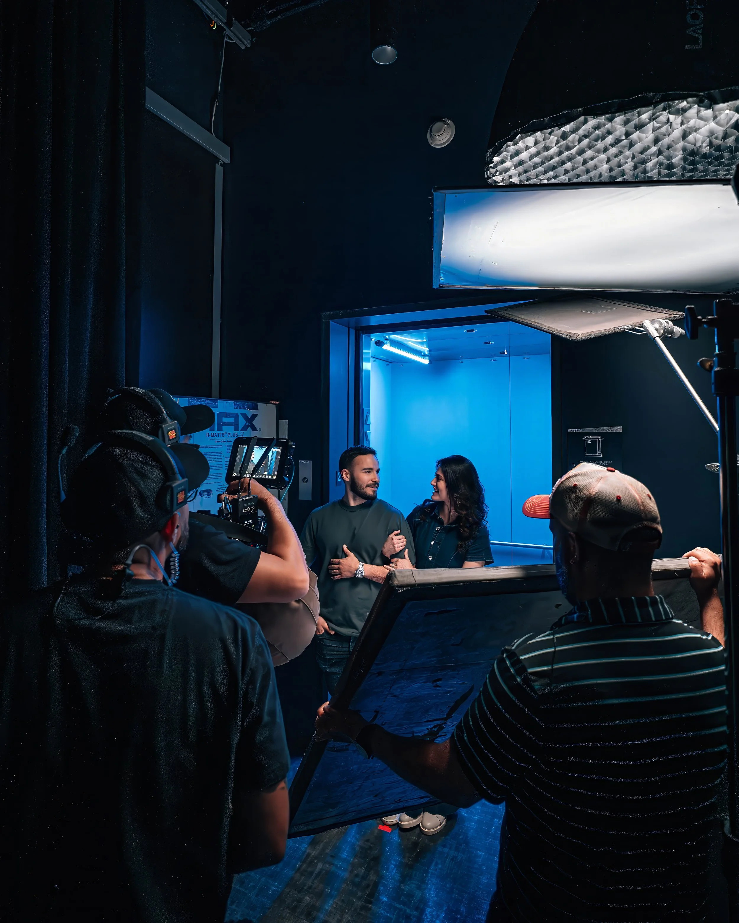 Film crew shooting a two person interview scene with professional lighting during a commercial video production.