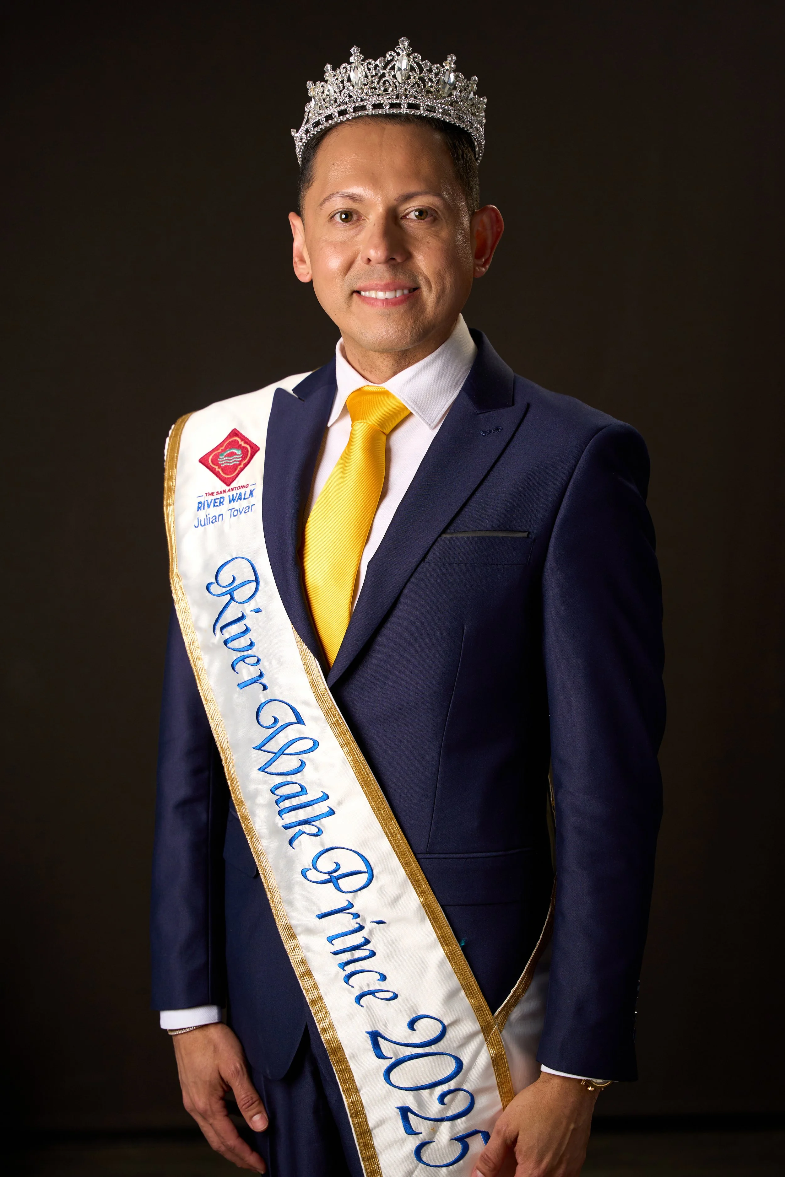 Formal studio portrait of San Antonio River Walk Prince 2025 wearing crown and sash.