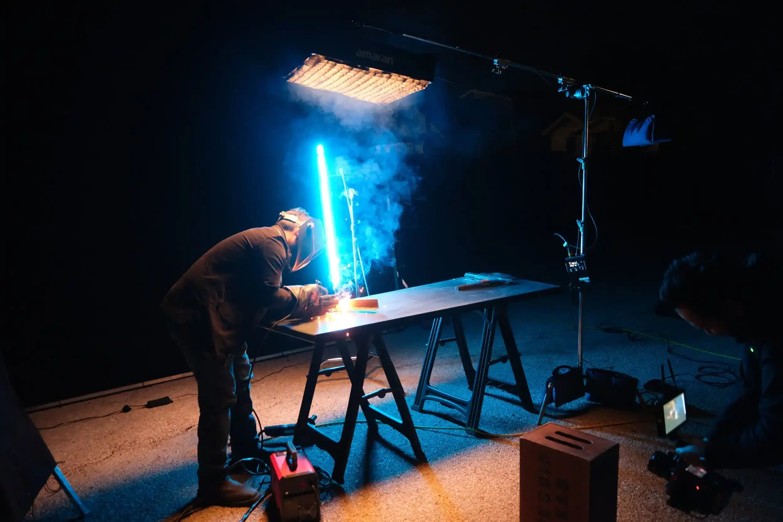 Neon light illuminates the welding process while being filmed by the Encima Media production crew.