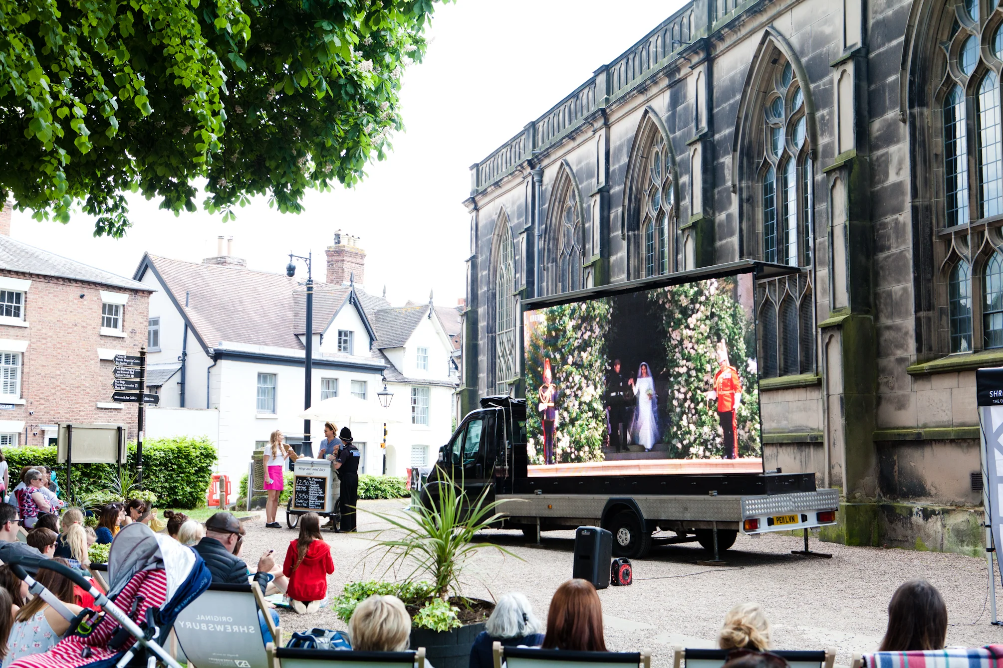  The big screen at St Alkmunds Church displaying the Royal wedding, with Alice Northrop, a policeman and ice cream cart in the background. 