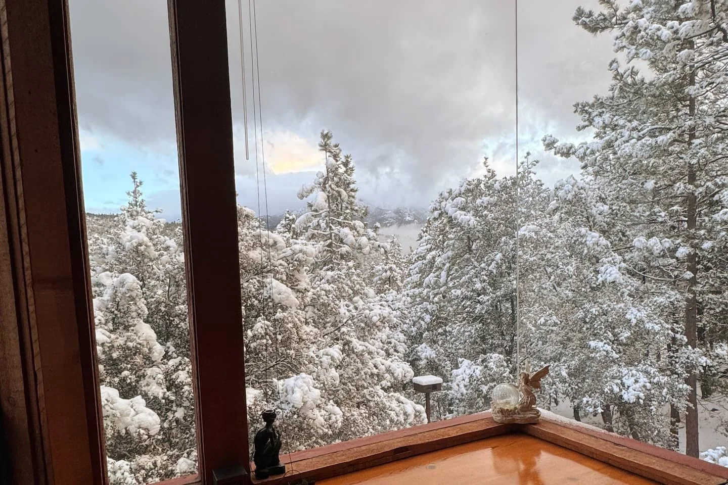 Desk overlooking snowy mountains and winter treetops from inside Faerie House Idyllwild cabin