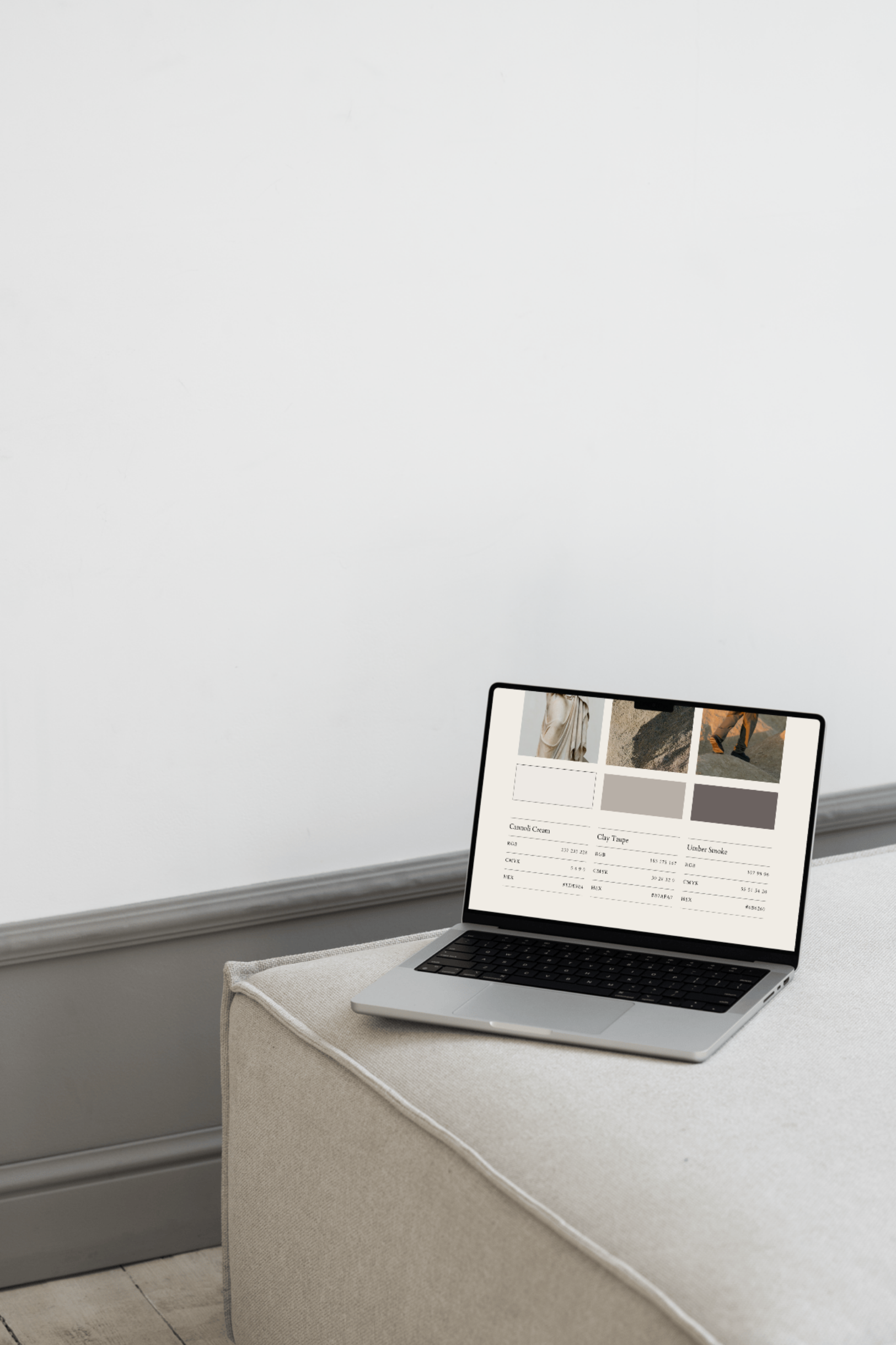 Open laptop on a light-colored fabric-covered surface, displaying a screen with color swatches and product details against a plain white wall.