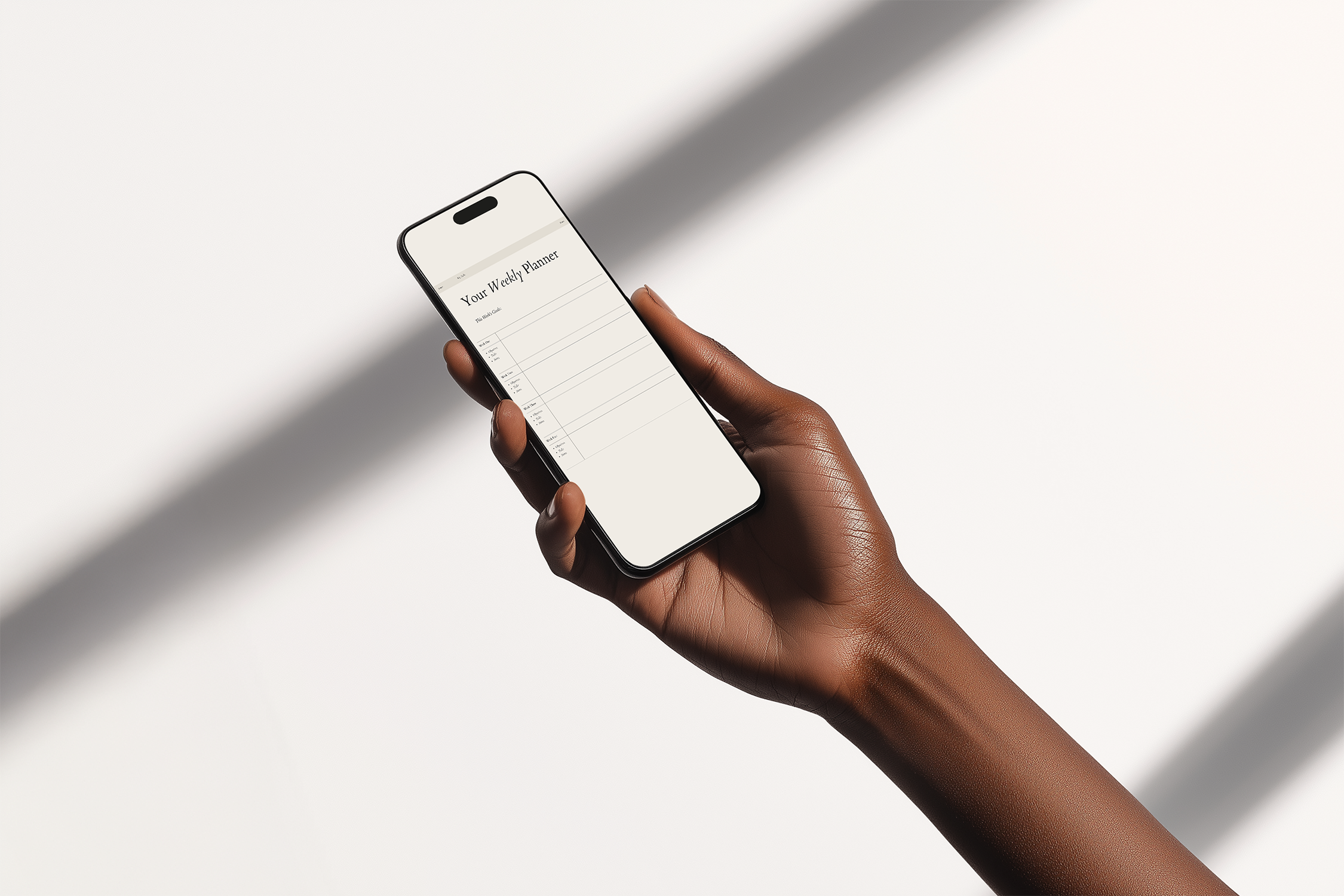A person with dark skin holding a smartphone with a weekly planner app open on the screen against a plain white background with shadows.