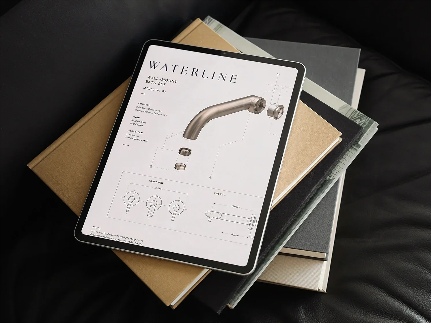 Digital tablet displaying technical drawing and specifications of a wall-mounted bath set faucet, resting on a stack of books.