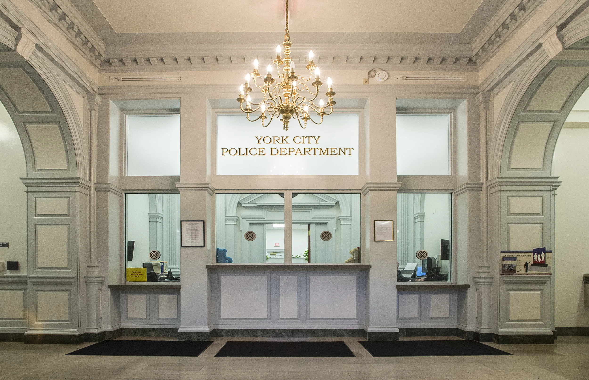 When the City of York determined the current City Hall Building was undersized for administrative operations, a move to an existing building downtown was made. The 132-person Police Department was the only function to remain in the four-story facility at the corner of Beaver and King Streets. Based on a feasibility study developed by BHA, City officials determined the location of City Hall made it an ideal candidate for renovation and would allow adequate space for a modern police facility. Though limited by a small footprint, the final design solution separates the demands of holding, patrol, detective, and administration. BHA developed a detailed program that was used to create a successful design solution. The building is organized to allow officers convenient access to evidence processing, duty bags, and locker facilities. Detectives use a secure entrance and have direct access to holding and interview rooms. Regrading of the tight site provided access to a two-car sallyport on the lower level with direct access to individual and group holding areas. Complying with state and national accreditation standards, individual holding areas are provided for male/female and adult/juvenile detainees. Construction was completed in four phases while the building remained occupied. Individual departments were moved several times to keep areas secure during construction. The seldom-used fourth floor is now used for training, fitness, and evidence storage due to the installation of a new elevator on the interior of the building, as the local Historical Review Board would not permit major exterior modifications. New perimeter fencing and the placement of an emergency generator also required Board approval. York City residents visiting the newly renovated building have limited access to the main lobby, which features impregnable transaction windows for Police and Records. An interview room and secure toilet room are the only other spaces accessible by the public. Upgrades included selected new finishes and major MEP upgrades. The design provides space for police administration, uniformed patrol division, investigative services, neighborhood enforcement division, support services/records, juvenile crime unit, prisoner handling, evidence, police support areas, armory, and locker rooms. The design complies with PA UCC, IBC building codes, and CALEA police regulations.
