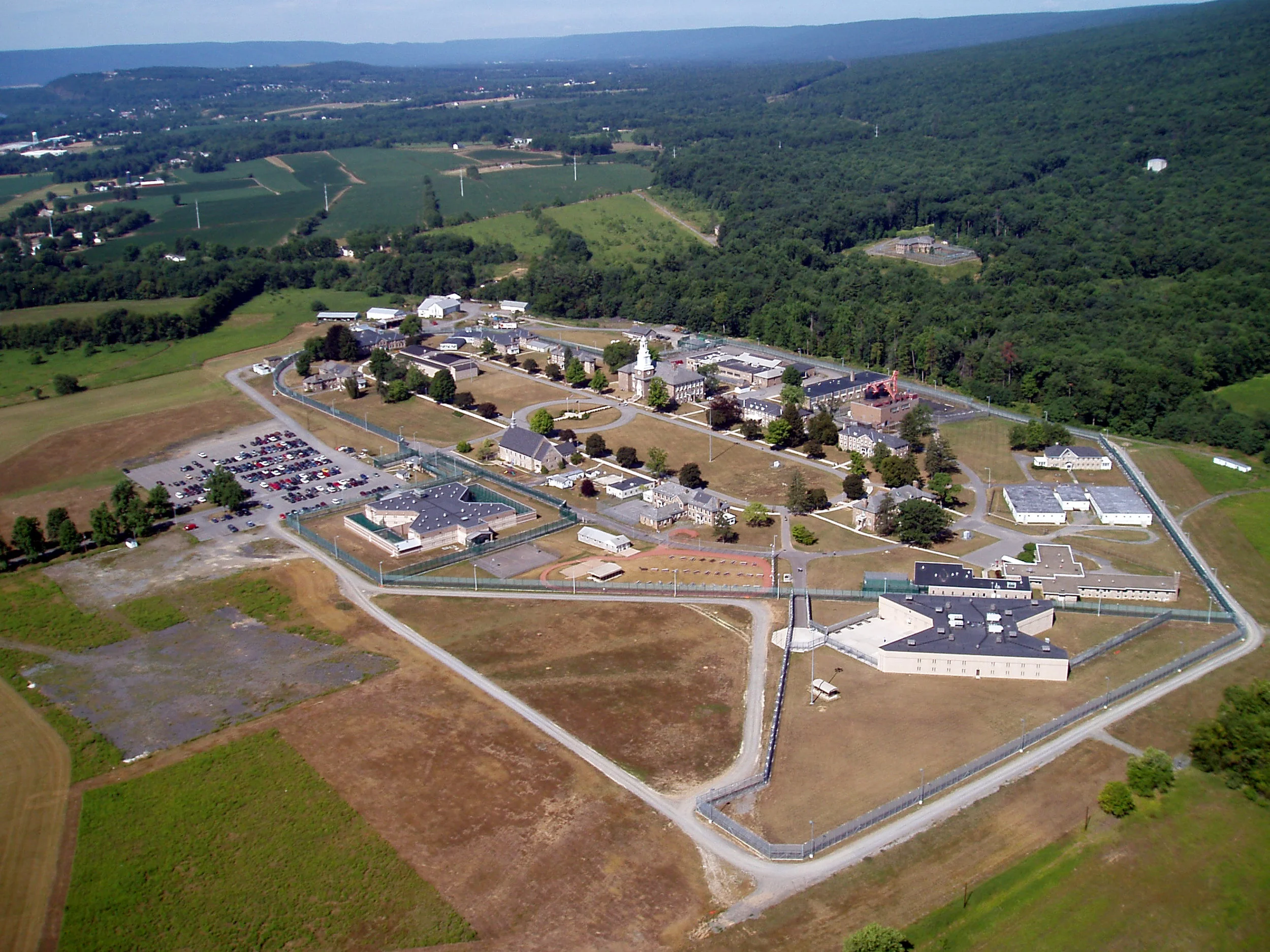 Buchart Horn Architects designed a new 33,400 SF, two-story, 128-cell L4 (close security) Housing Facility for the State Correctional Institution at Muncy. BHA provided architecture; structural, mechanical, and electrical engineering; landscape architecture; and other professional services as well as construction administration services. SCI Muncy was experiencing critical levels of overcrowding and required an extreme fast-track for design and construction of additional housing. Having previously designed a similar housing unit at Muncy, BHA was asked to design the new unit. The project construction was split into three separate contracts in order to expedite the schedule. The first contract, by others, provided for early fabrication of the precast concrete cells with interior furnishings for bunks, desk, security mirror, wardrobe lockers, and shelf, all manufactured by the Department of Corrections, Correctional Industries. The second contract was a site package for work outside the security fence perimeter of the operating correctional institution. Erosion and sedimentation control; site preparation, and work to clear the space for the building foundation slabs-on-grade; and masonry foundation walls were included. The 64 double-cell modular precast cell units were then set into the foundation construction. The final contract tasked multiple primes with constructing Buchart Horn Architects design around the precast cell units. General construction covered underground utilities, structural steel, exterior precast concrete walls, interior masonry, roof deck, floor slab, roofing system, door and windows, etc. HVAC construction covered ductwork, piping, mechanical equipment room, and four 6200 cfm energy recovery rooftop units with central steam supply and energy recovery wheel for heating and electric direct expansion for cooling. Plumbing construction covered the underground and above ground piping and plumbing fixture connections, etc. Electrical construction covered the excavation and trenching of the electrical service duct bank and supplying and setting a pad-mounted transformer and automatic transfer switch. This contract also covered the power wiring for the mechanical system equipment, smoke evacuation equipment and installation of the fire alarm system. The electrical service, associated electrical systems, and the security system including door control and data/telephone system were all designed by BHA. The project used a systematic process for commissioning to ensure that all building systems performed interactively according to SCI Muncy's design intent and operational needs.