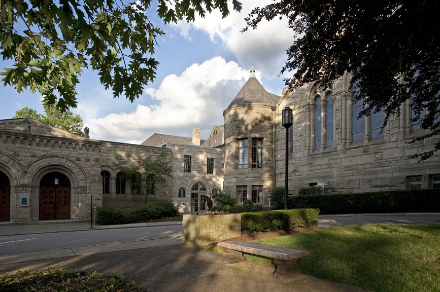 The historic Shadyside Presbyterian Church, originally designed in 1890 by Shepley, Rutan & Coolidge, the successor firm of famous American architect Henry Hobson Richardson, was in need of enhancements in order to better serve its evolving and diverse congregation. Buchart Horn Architects developed a program that focused on re-creating and re-inventing spaces that were underutilized in the building along with developing two small key-point additions to create a more cohesive facility. Prior to the renovation, dining and fellowship occurred in the gymnasium one level below the church sanctuary and there was no obvious connection between these spaces. Wayfinding through the facility was circuitous and primary entry points to the school and church offices were enigmatic to the first-time visitor. BHA established connectivity between these important but disparate spaces by inserting new, centrally located public gathering and circulation spaces between the Westminster Place and Amberson Avenue entry points. On the Westminster Place façade a well pronounced compatible stone entrance addition was created that incorporates and encloses the adjacent cloister which now welcomes congregants and visitors alike to this main floor entry point. Beyond the cloister was an outdoor courtyard that is now enclosed to offer a sky-lit atrium space supporting after-church fellowship with the cloister as passageway to the main worship space on the west and to provide an ancillary space to the church’s chapel and parlor on the east. The chapel was renovated as well with ornate stencil work on the walls and ceiling of the altar area and stenciled border patterns around the coffers of the chapel’s main cathedral ceiling. Custom designed chairs with carved backs reflecting the muntin patterns of the staining glass windows within the chapel replaced the fixed pews. These changes coupled with new cork flooring and new lighting recreate the chapel as a rich ceremonial space with flexibility for multiple functions of various sizes. A new central lobby space was also developed beyond the atrium creating an information center and waiting area that links all of these main level spaces with the ground floor through an adjacent sky-lit stair tower/entry addition. This entrance presents to Amberson Avenue via the circular drive at the ground floor level and provides a more prominent access point to the newly renovated nursery and Sunday school facilities with a small lobby space of its own. The adjacent gymnasium on this level is now renovated into a well appointed multi-purpose parish hall that can support over 200 people for a formal banquet event and a separate classroom/lecture hall with A/V systems to support any style presentation.