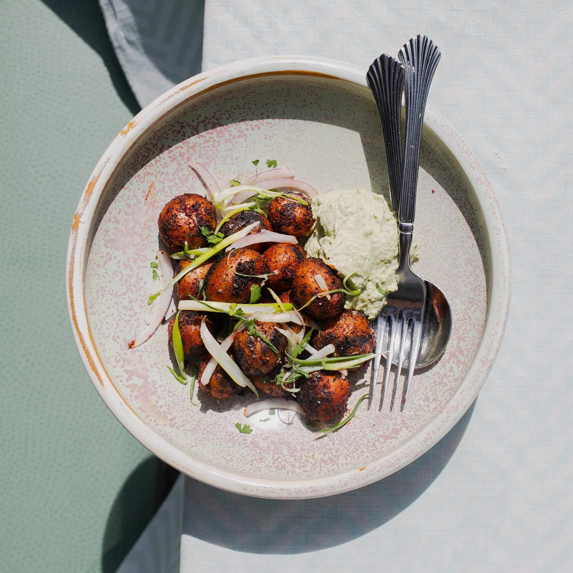 A bowl of Indian street food, likely pani puri or golgappa, filled with spicy tamarind water, topped with chopped onions, cilantro, and served with a side of green chutney.