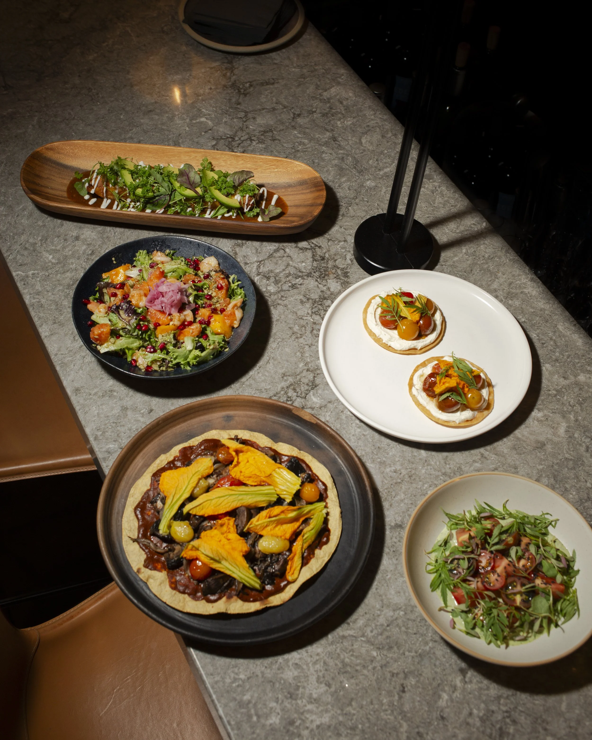 Assorted dishes including salads, a gourmet pizza, and appetizers on a kitchen counter.
