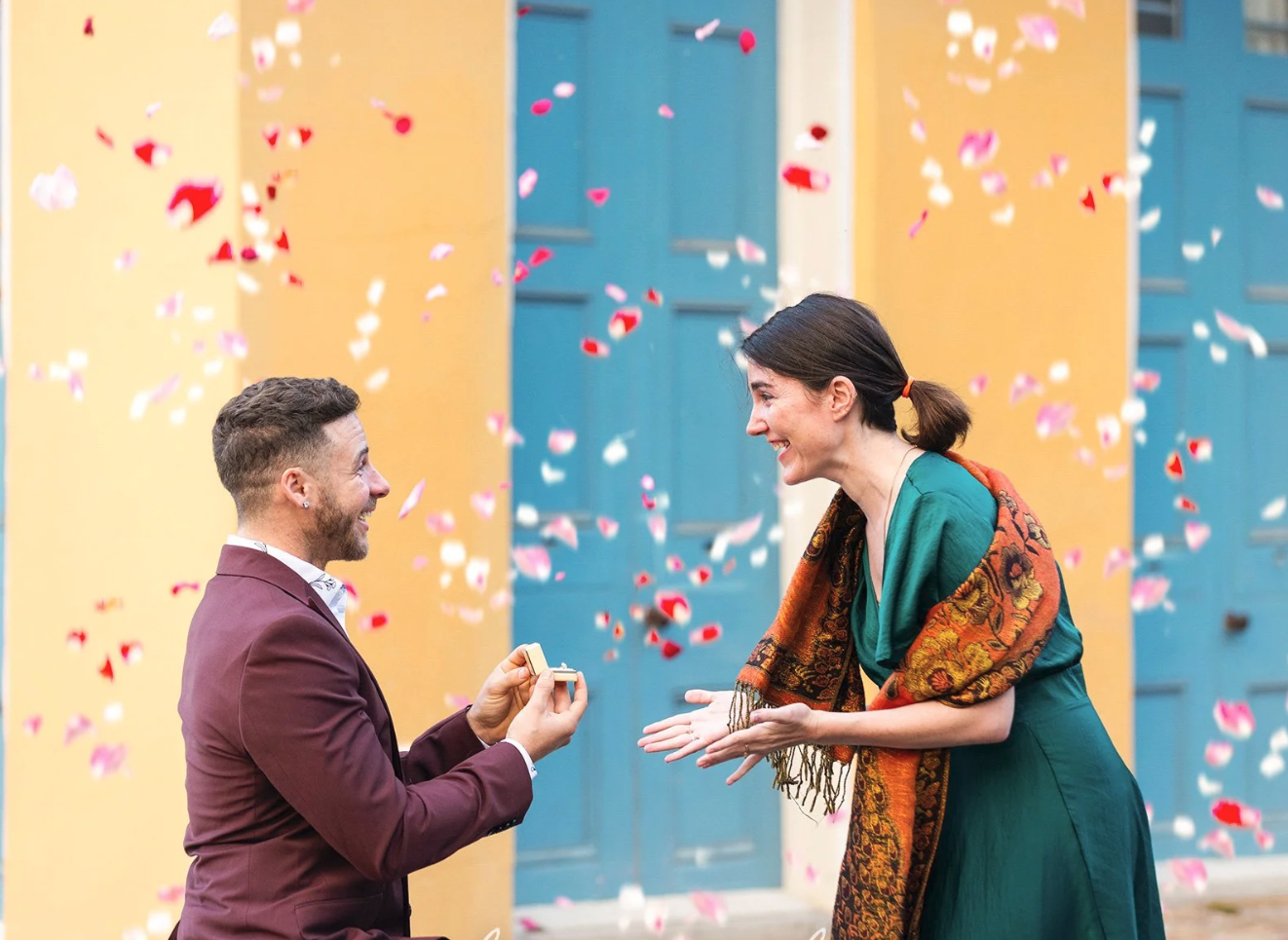 A man proposes to his girlfriend in New Orleans while rose petals fall from above.