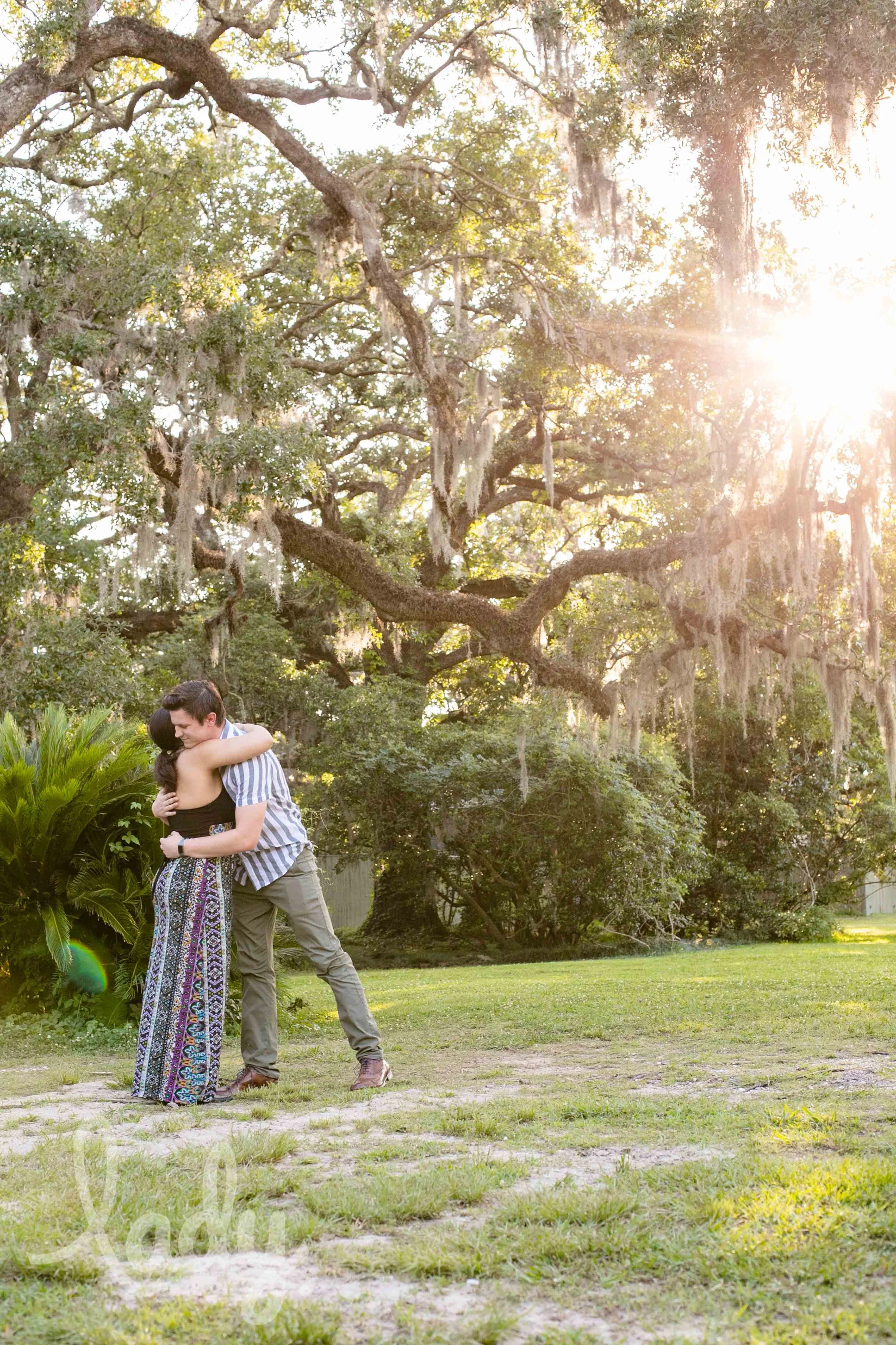 A couple embraces after a surprise proposal in Audubon Park.