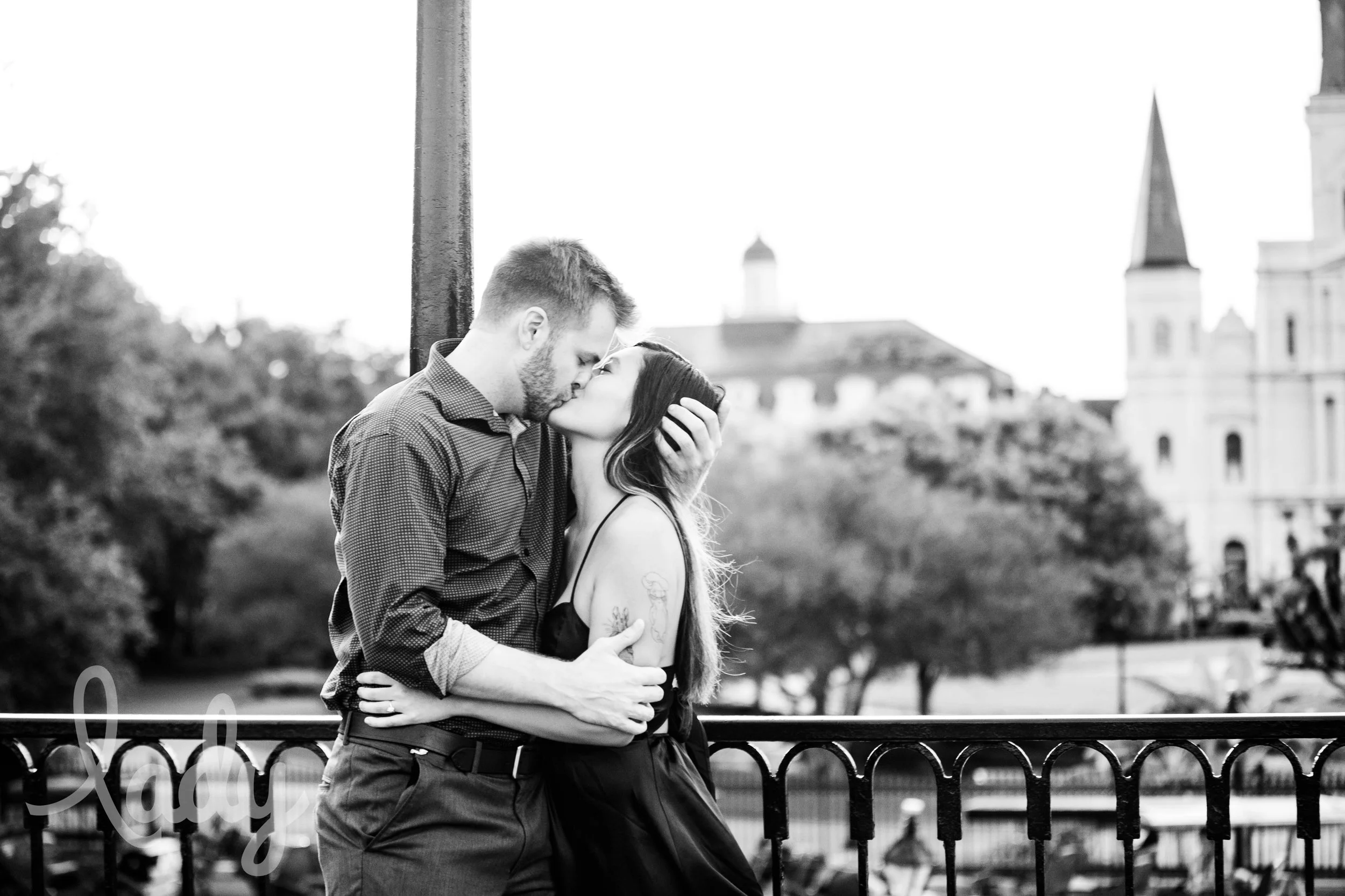 A  couple kissing in front of St. Louis Cathedral.