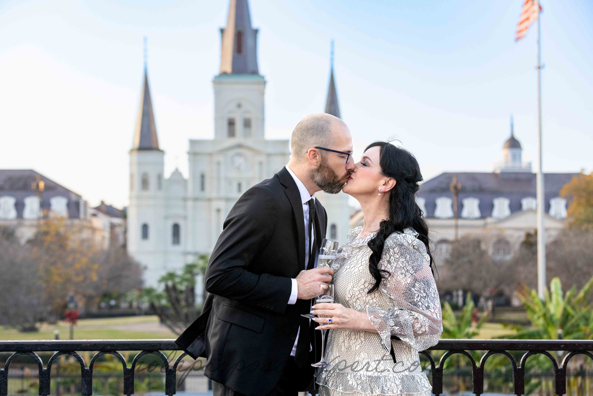 A newly engaged couple shares a kiss and a champage toast following their surprise proposal overlooking Jackson Square in New Orleans.