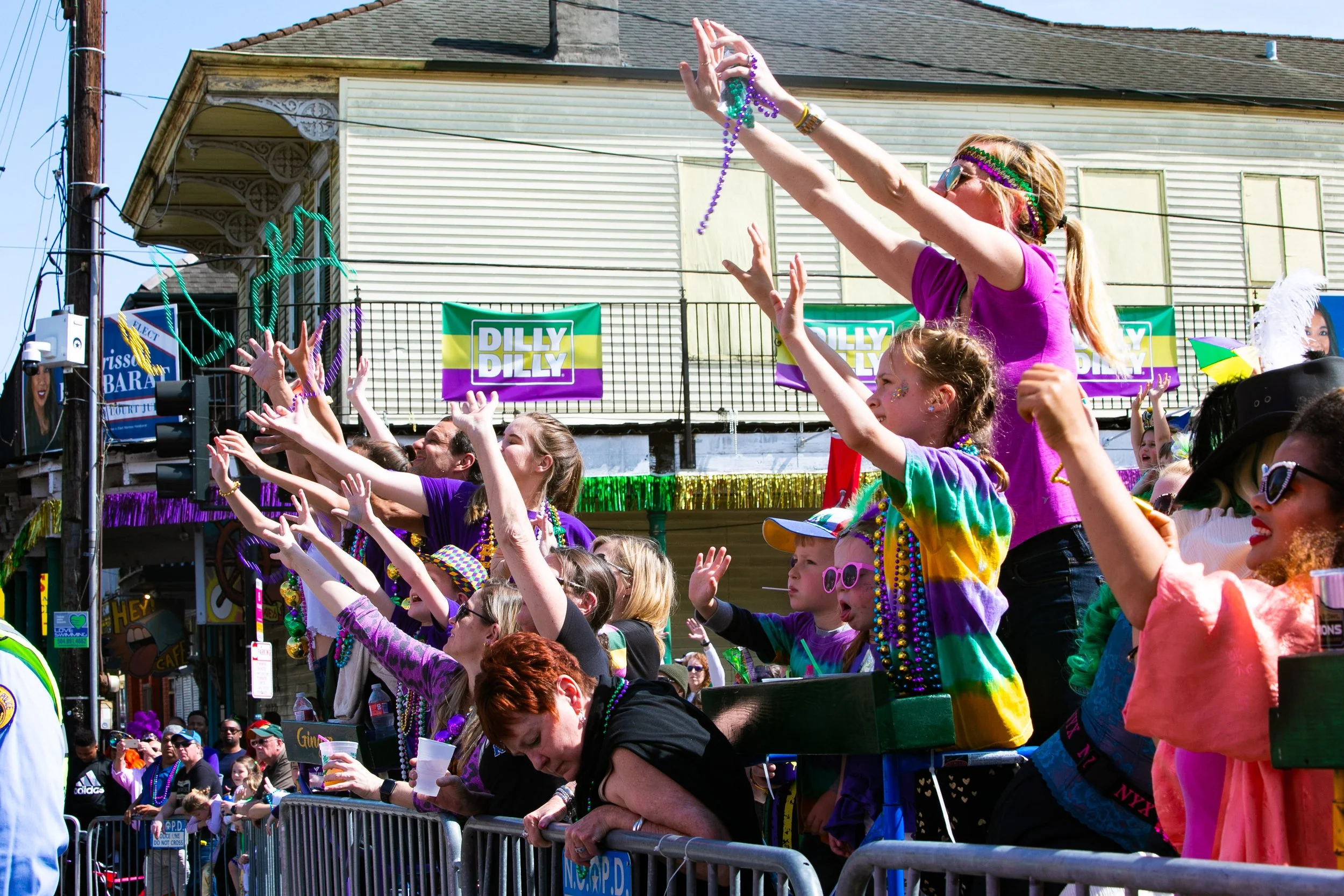 Parade goers dressed in purple green and gold stand on a barricade catching beads being thrown during a mardi gras parade on st charles avenue in New Orleans.