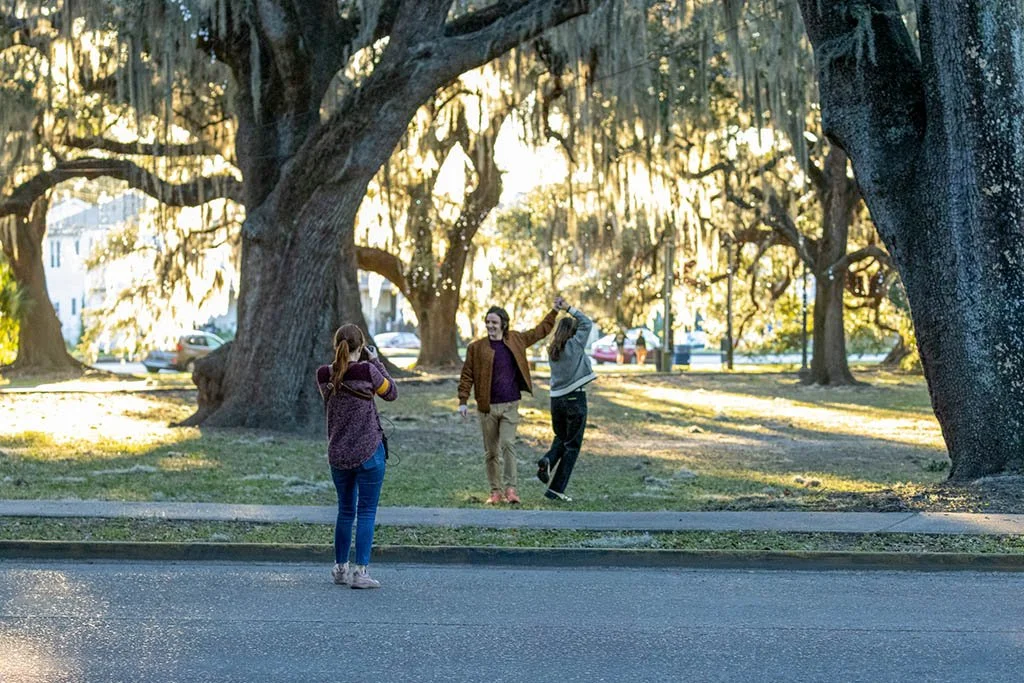 A professional photographer photographs a couple in New Orleans city park after their surprise proposal.
