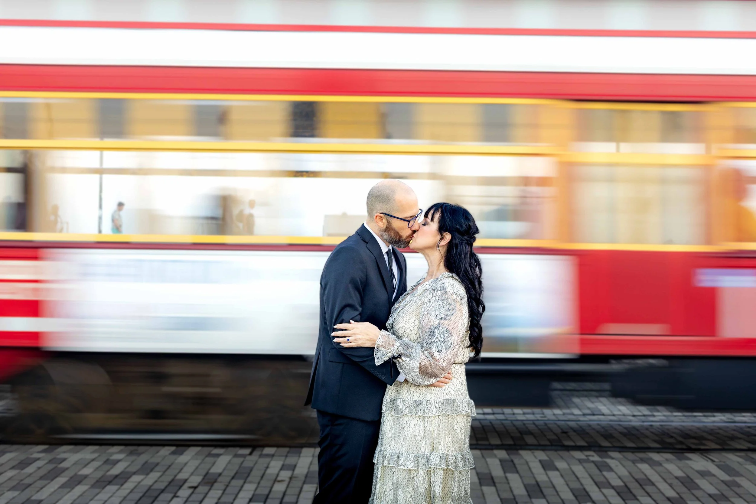 A newly engaged couple kisses in front of a riverfront streetcar in New Orleans.