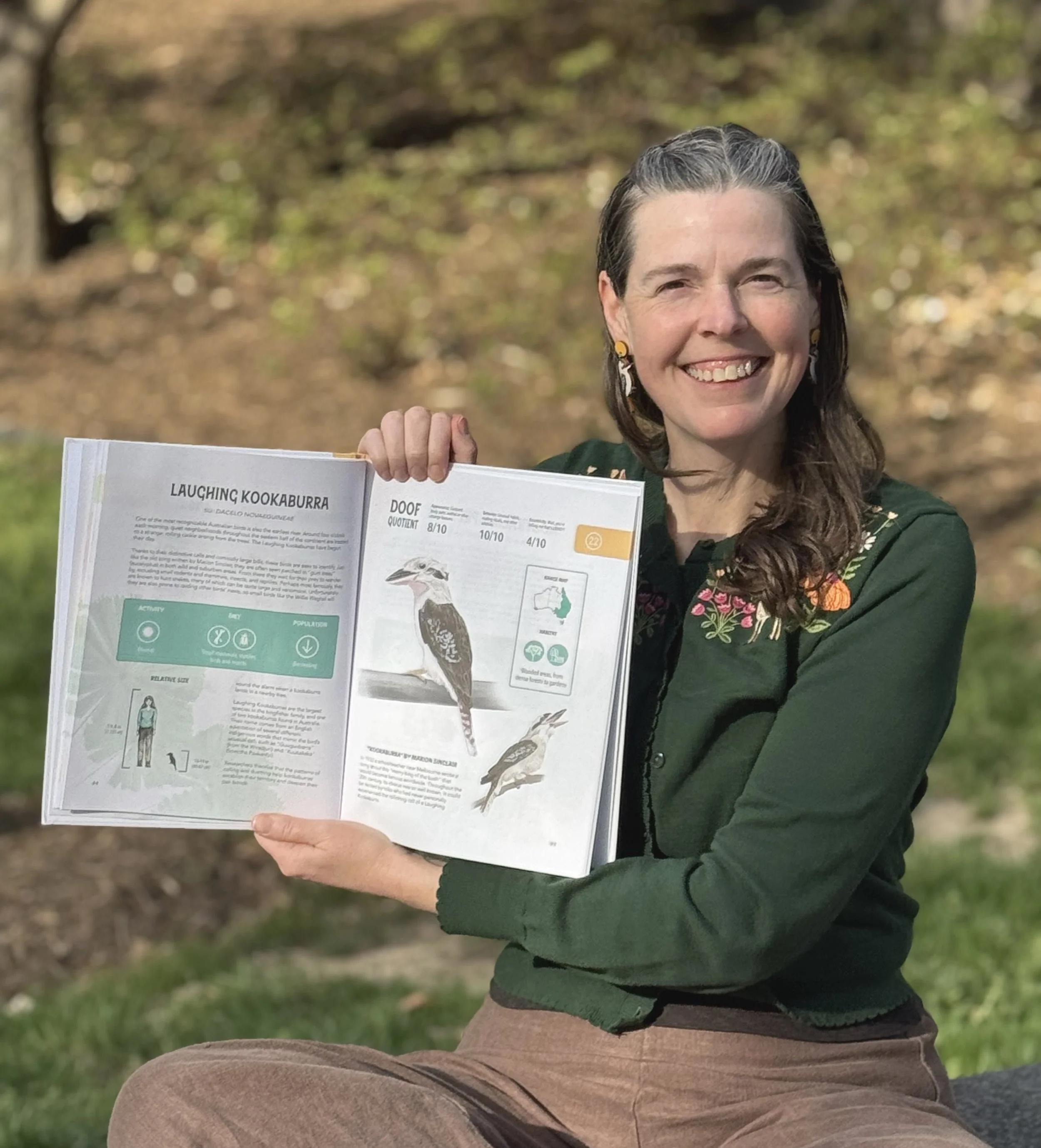 Photo of the author holding her book open to show a Laughing Kookaburra