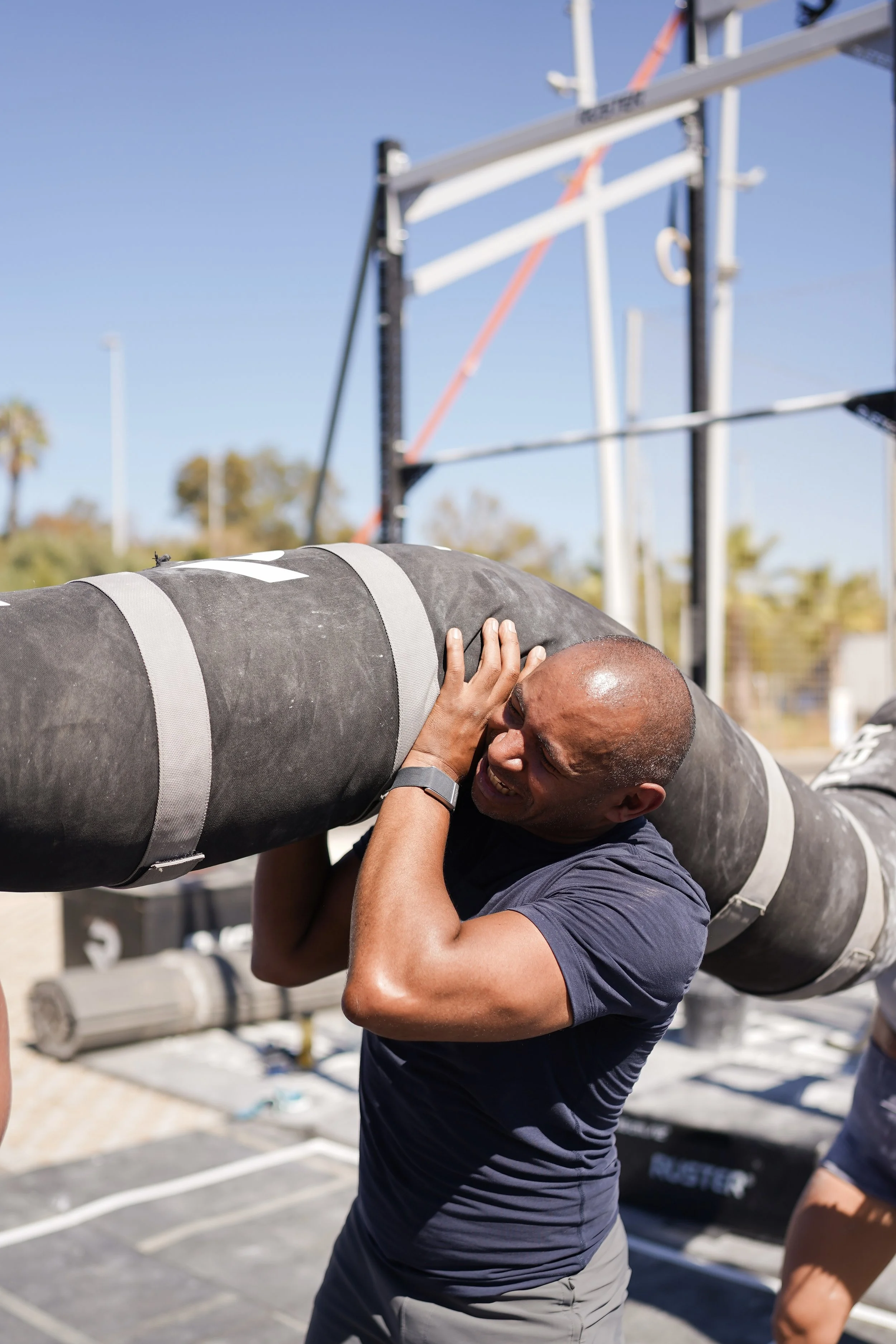 Co-Owner and Coach Dan lifting a Worm as part of a team work out outside in the sunshine