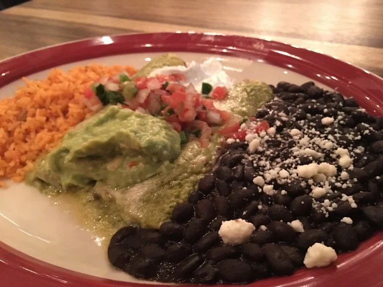 Pork enchiladas with poblano cream sauce, black beans and rice topped with guacamole and pico de gallo. Photo by Rachael Worthington.