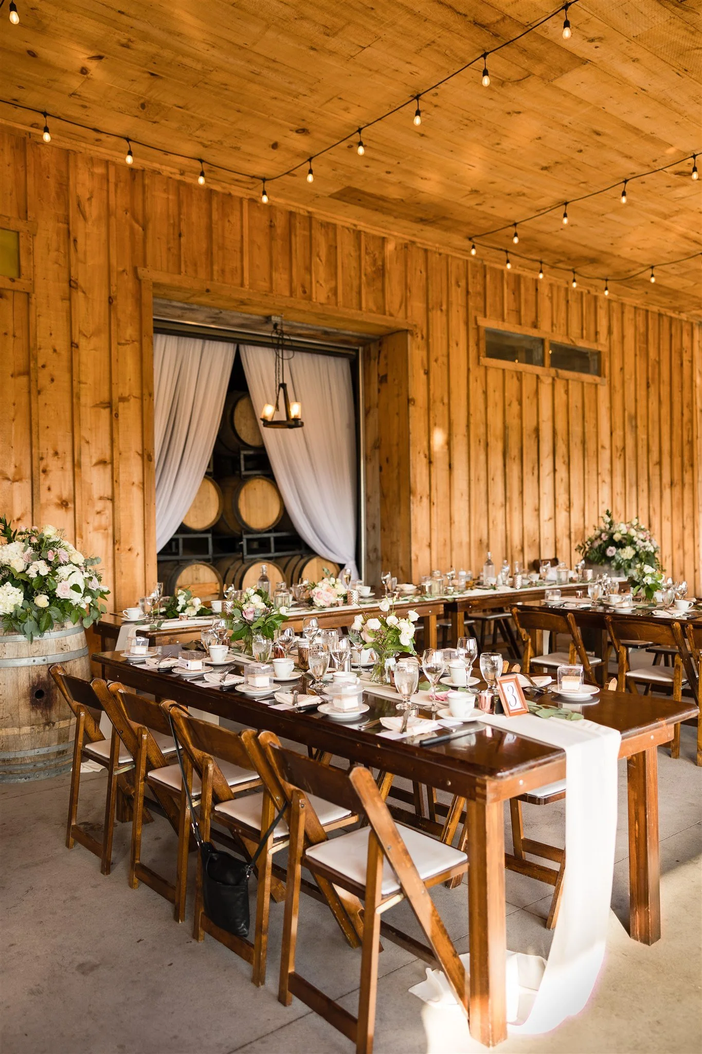 Chiffon runners on harvest tables with open draping by barrel wall at Calamus Estate Winery