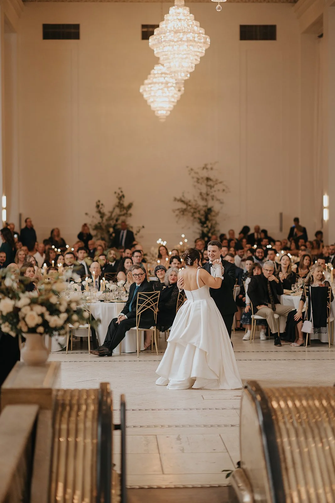 Arbor Midtown wedding reception with bride and groom dancing in a grand ballroom surrounded by guests and elegant candlelit tables in Rochester, NY.