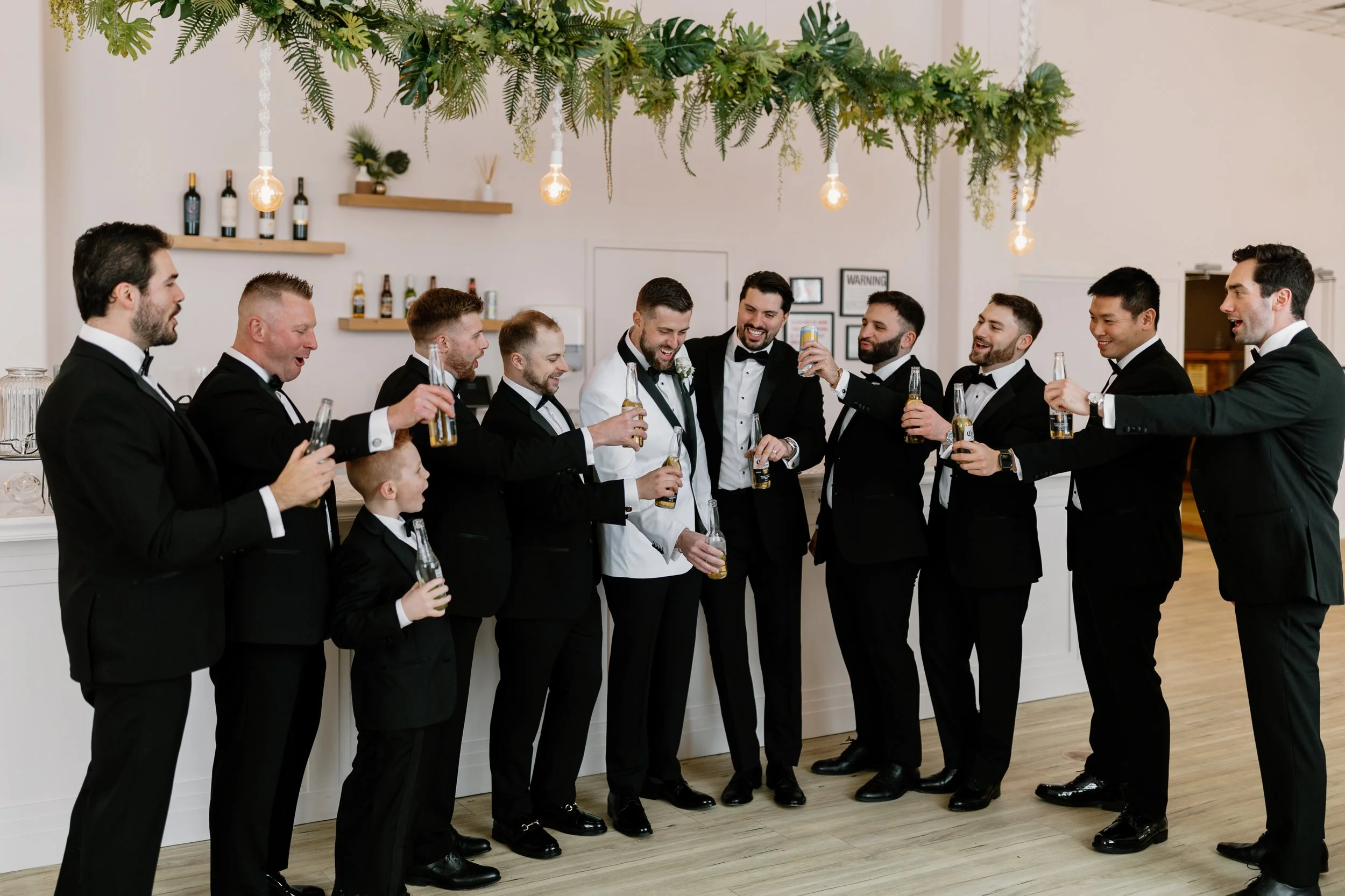 Arbor at the Port groom with groomsmen raising drinks in a bright modern wedding venue in Rochester, NY.
